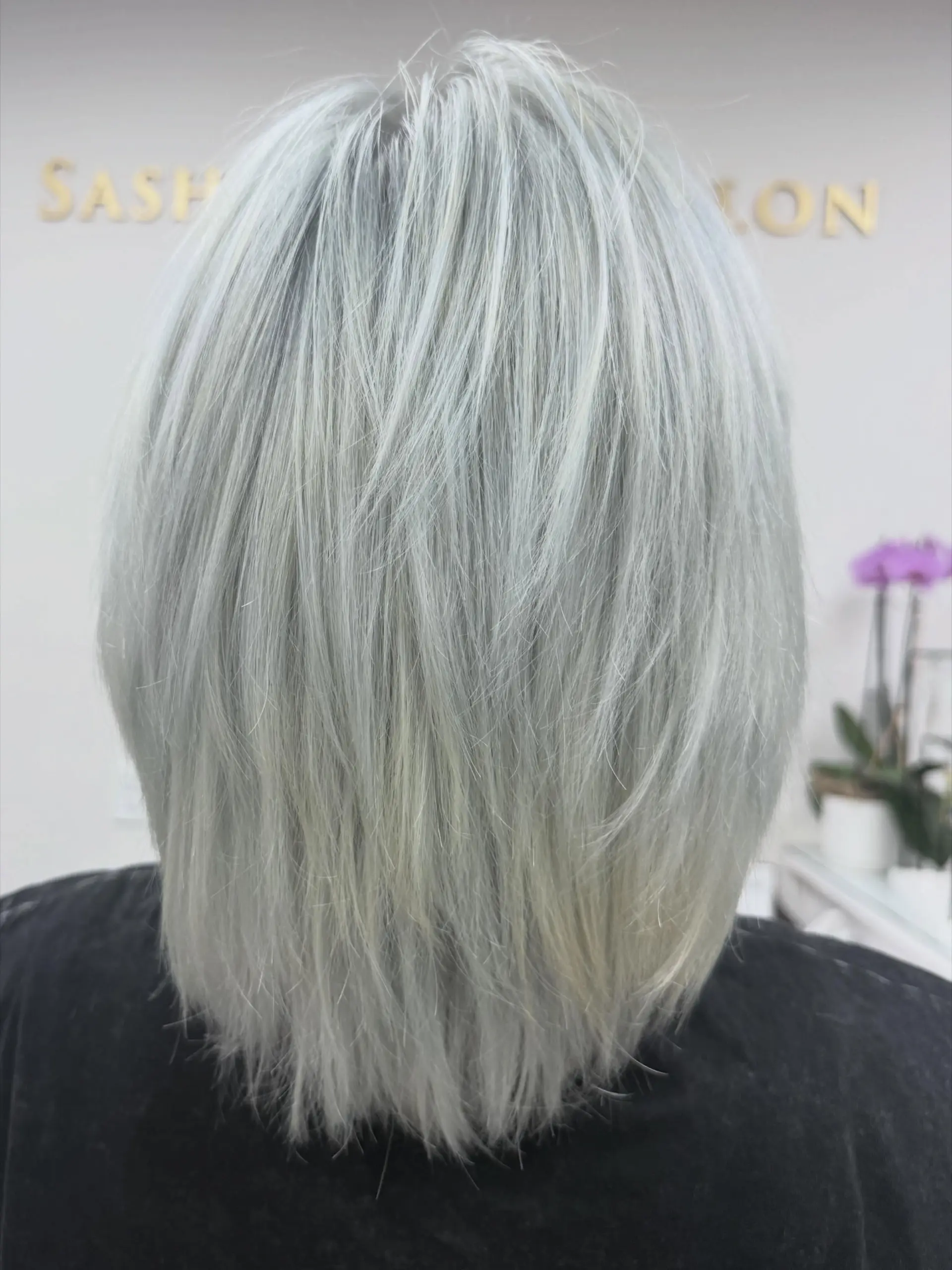 A textured neck-length bob styled with shattered layers in a cool, icy blue-steel platinum blonde. 1