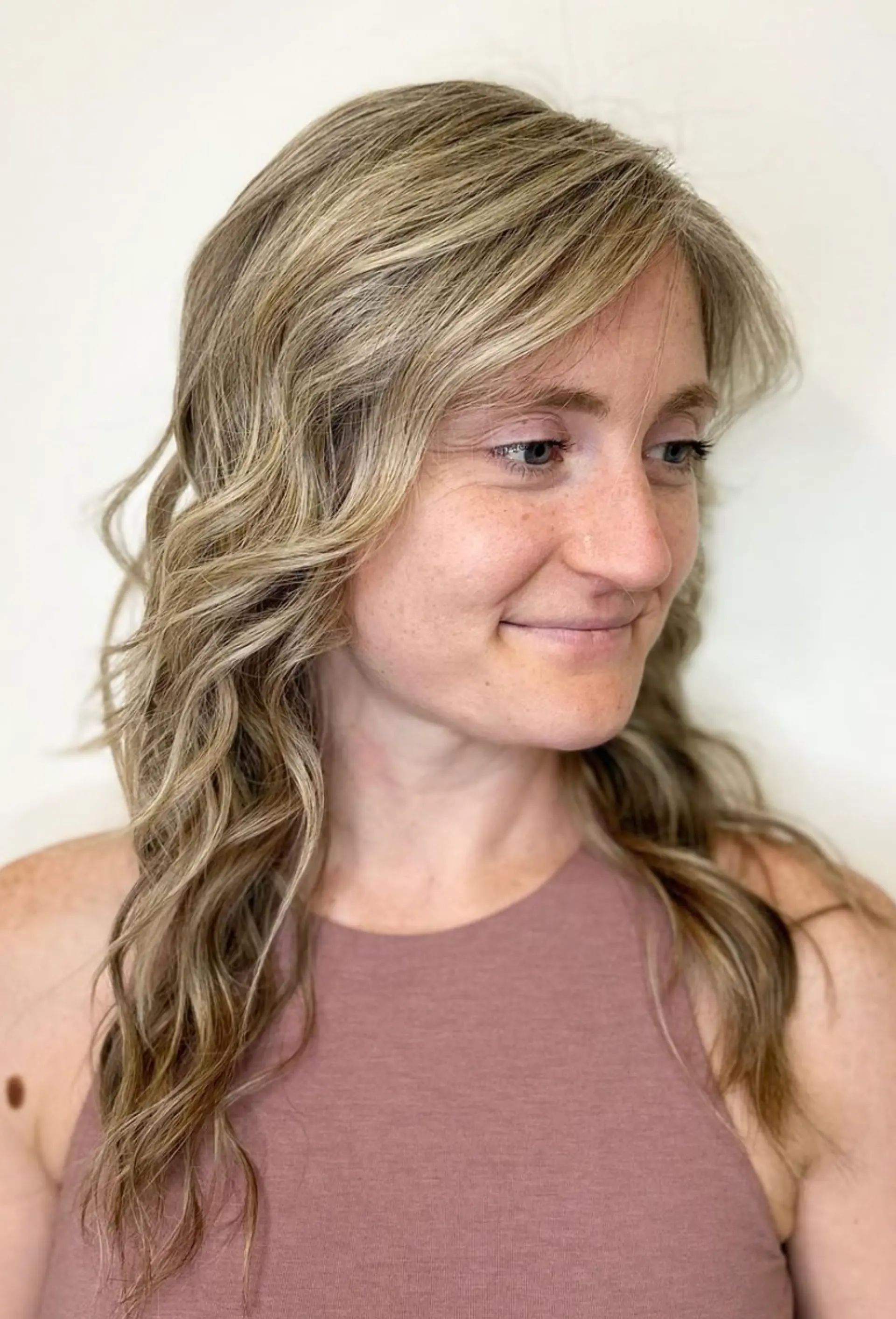 Long, wavy hair with a soft blonde base and honey highlights. The style features subtle waves, a side part, and a layered cut for added volume and movement.

Color by @simabeautynyc
 1