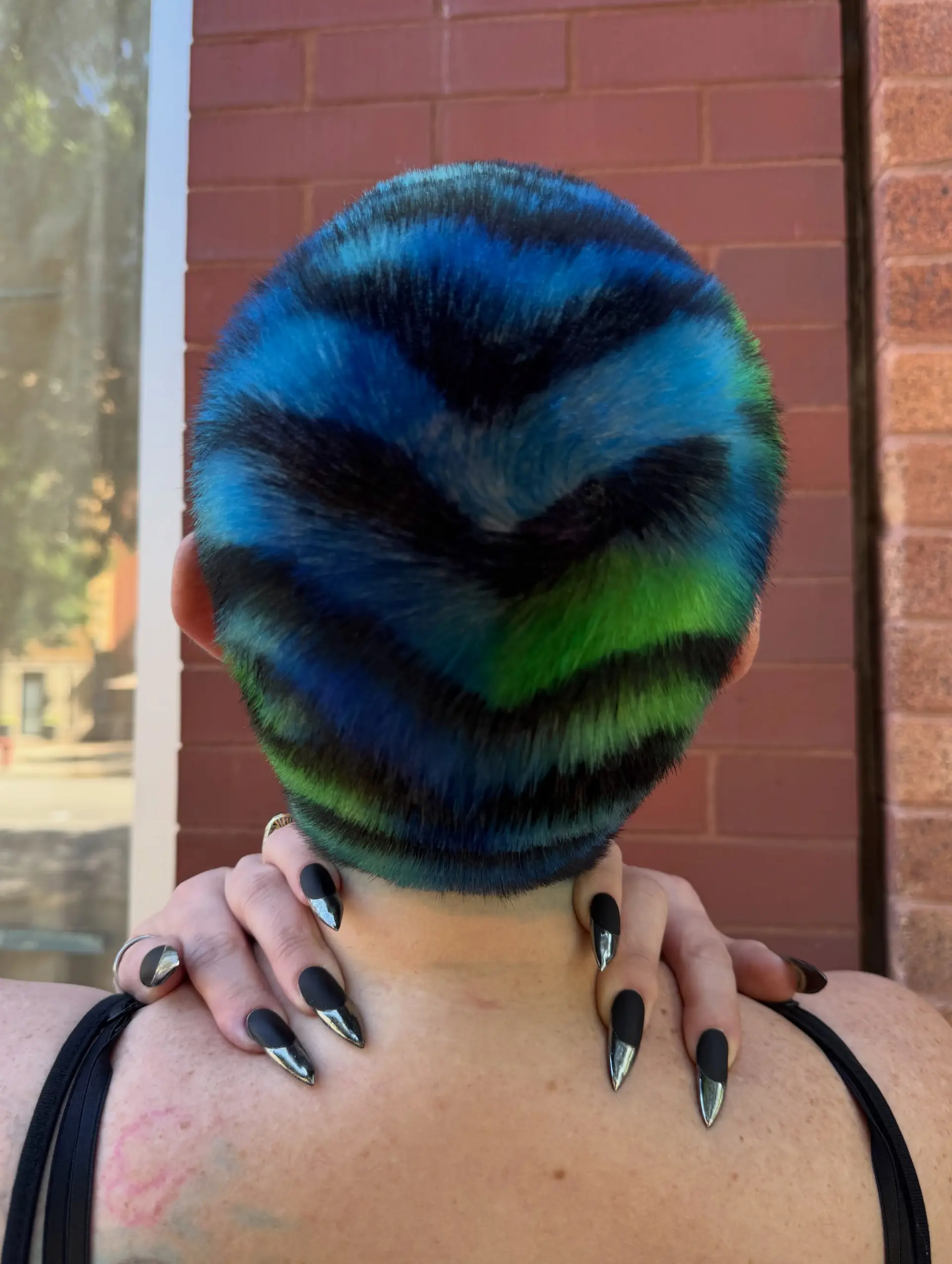 A closely buzzed haircut painted with vivid tiger stripes in electric blue, lime green, and deep black. 1