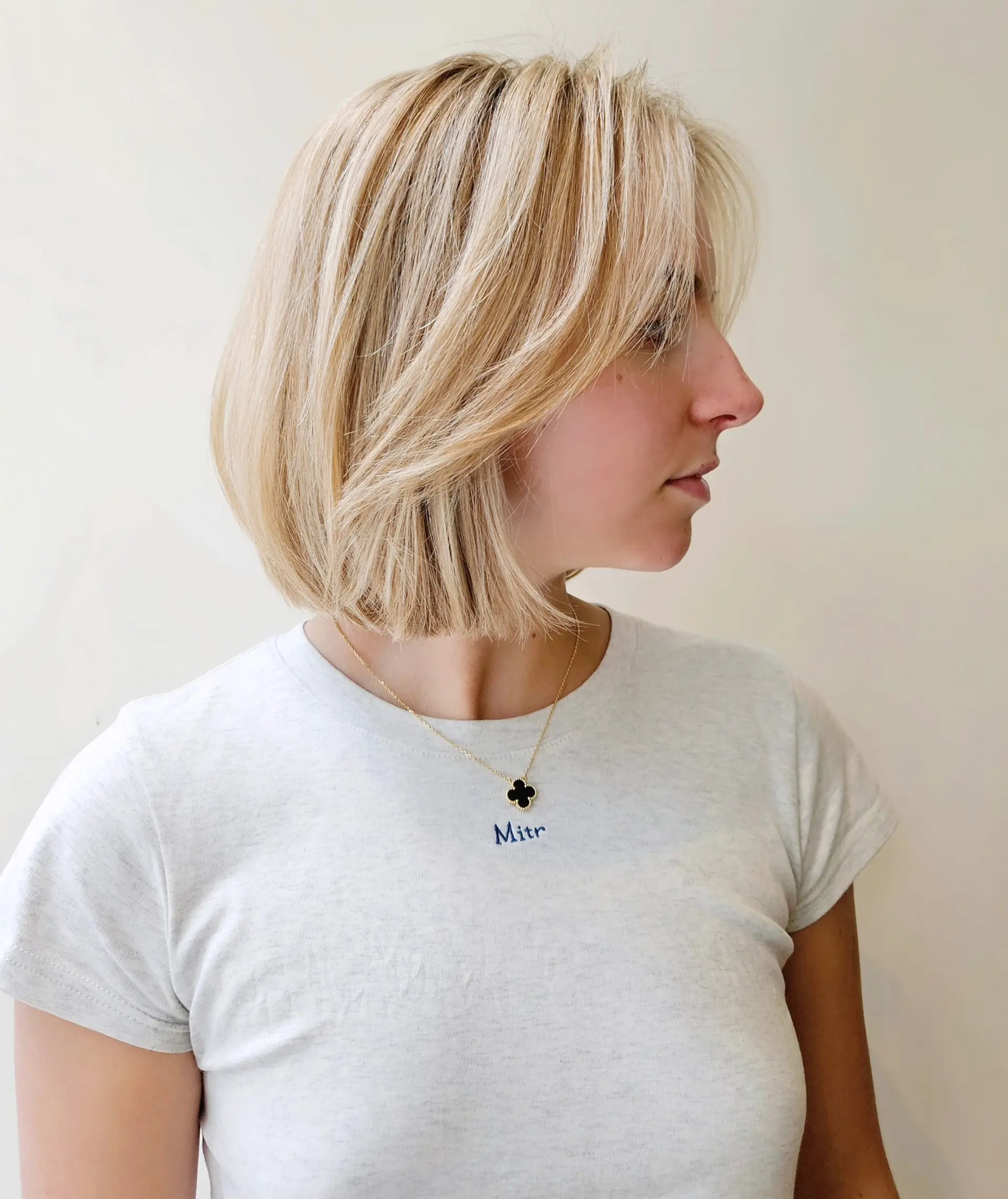 A chic chin-length textured bob cut featuring soft layers and wispy, side-swept bangs in a warm honey blonde tone. 1
