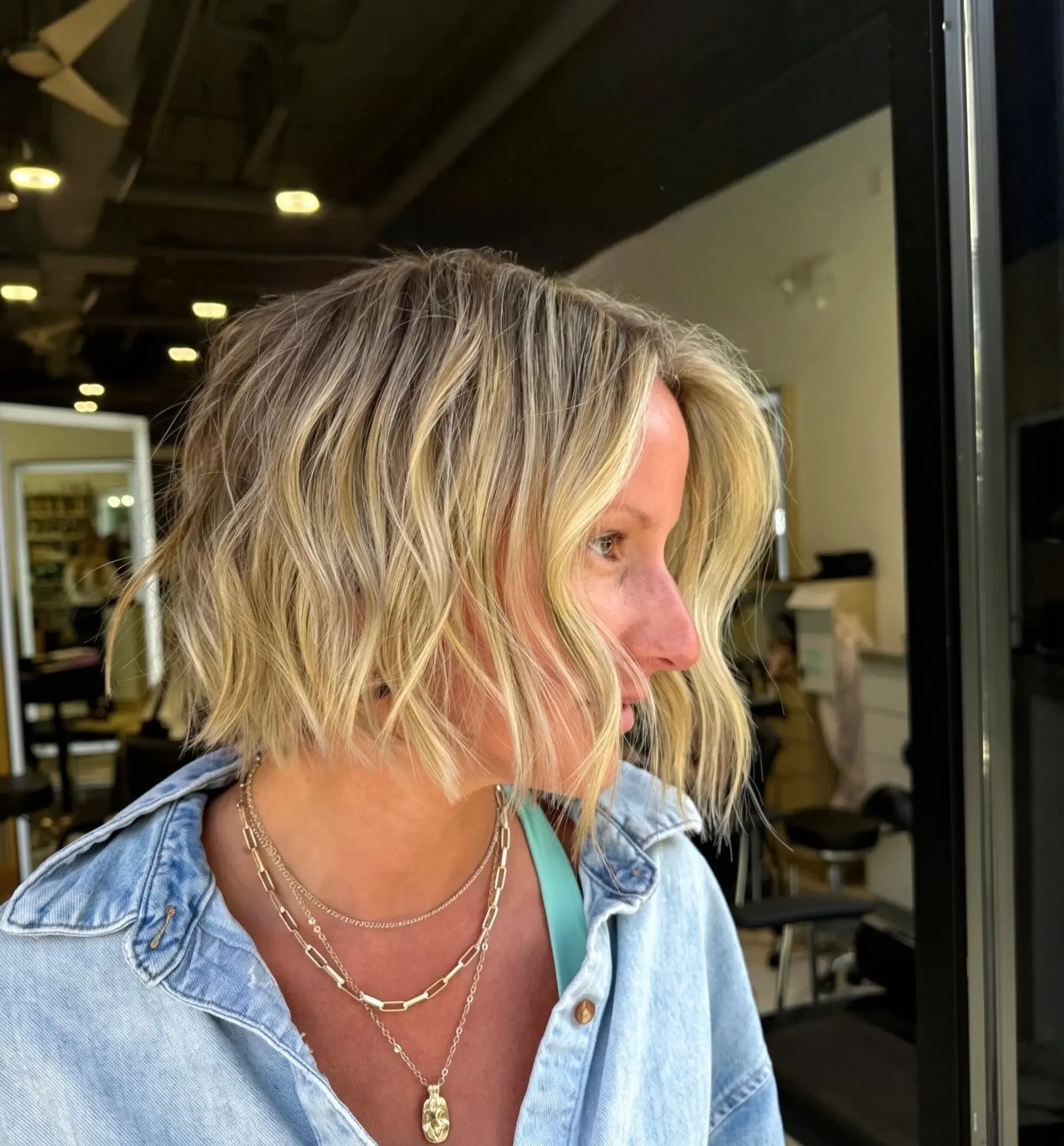 A textured chin-length bob cut styled with undone waves and multi-dimensional blonde highlights. 1