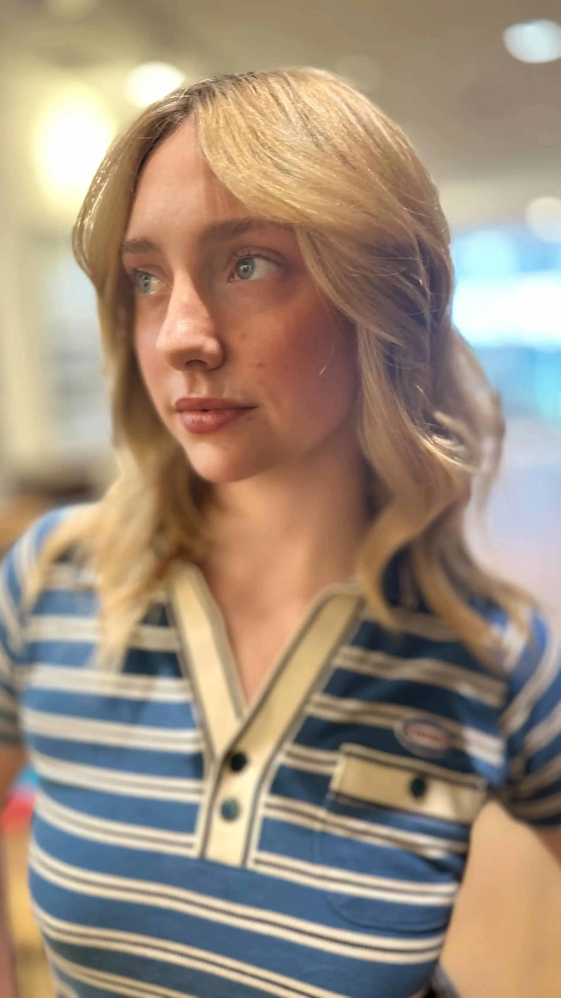 Medium-length warm blonde hair featuring soft waves and face-framing feathered curtain bangs. 1