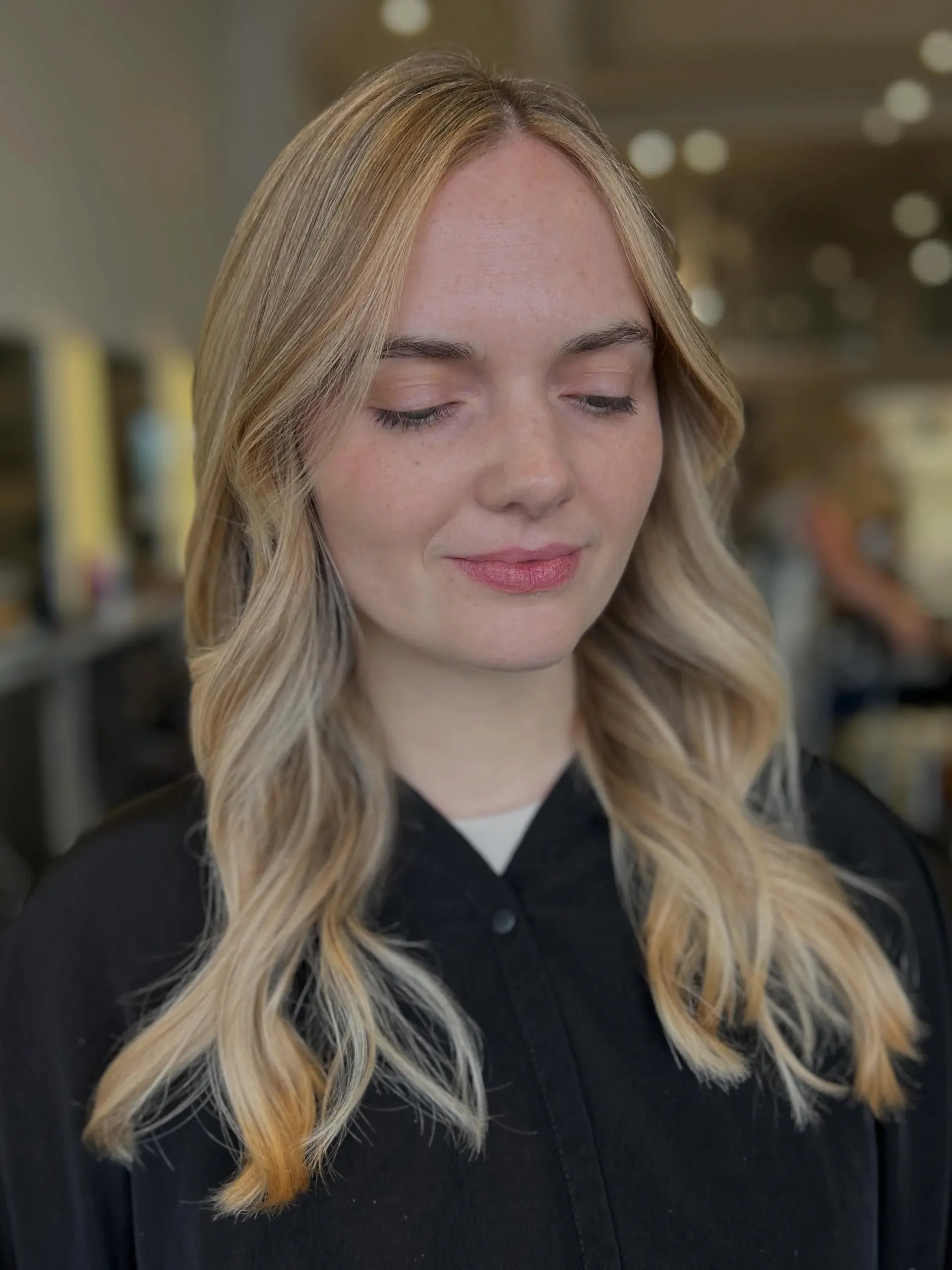 Luminous golden blonde full highlights styled into gentle, face-framing waves with a center part. 1