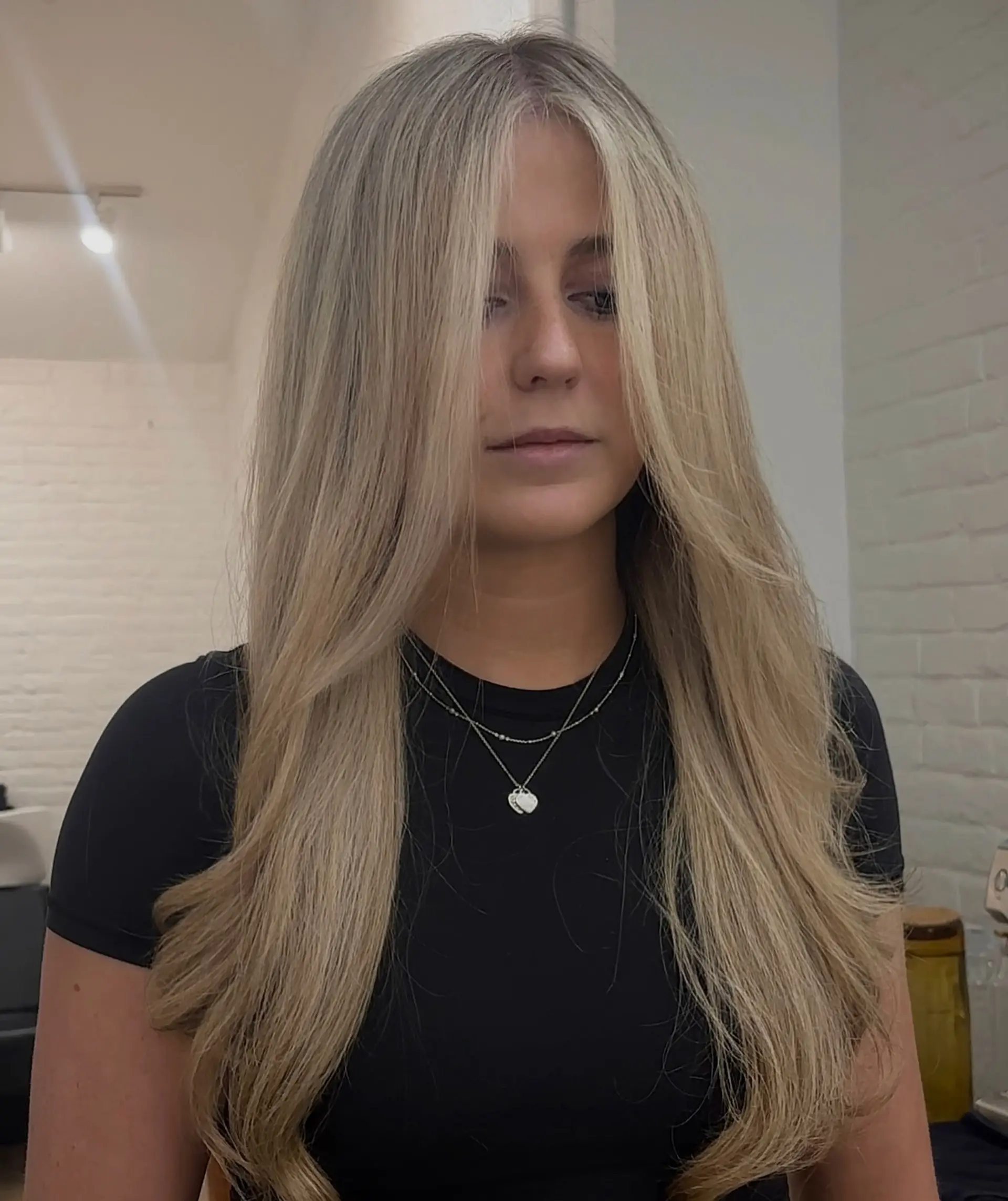 Long blonde hair cut with graduated face-framing layers and styled in a sleek, voluminous blowout. 1