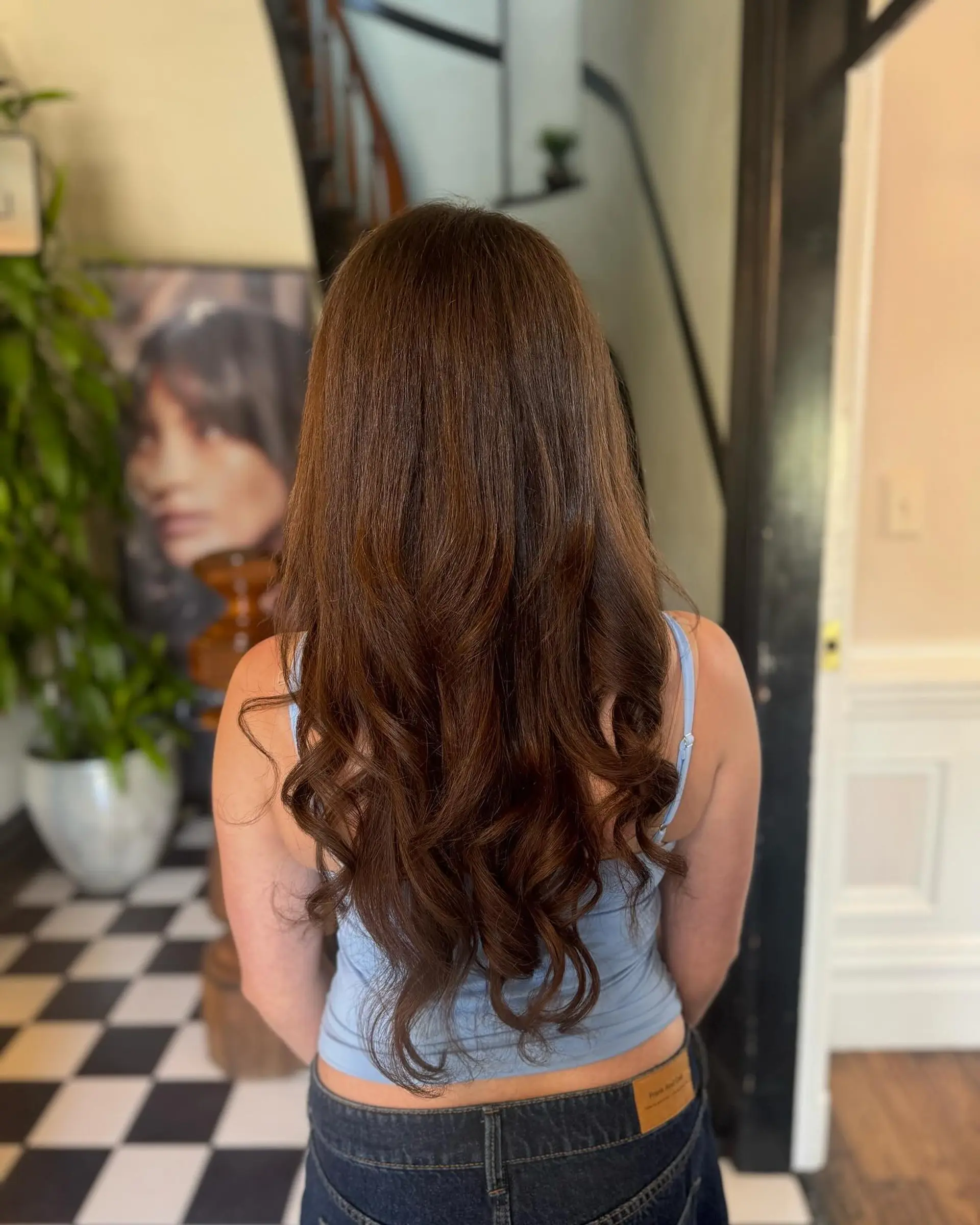Long warm brown hair smoothly blown out with soft, defined curls cascading through the ends. 1