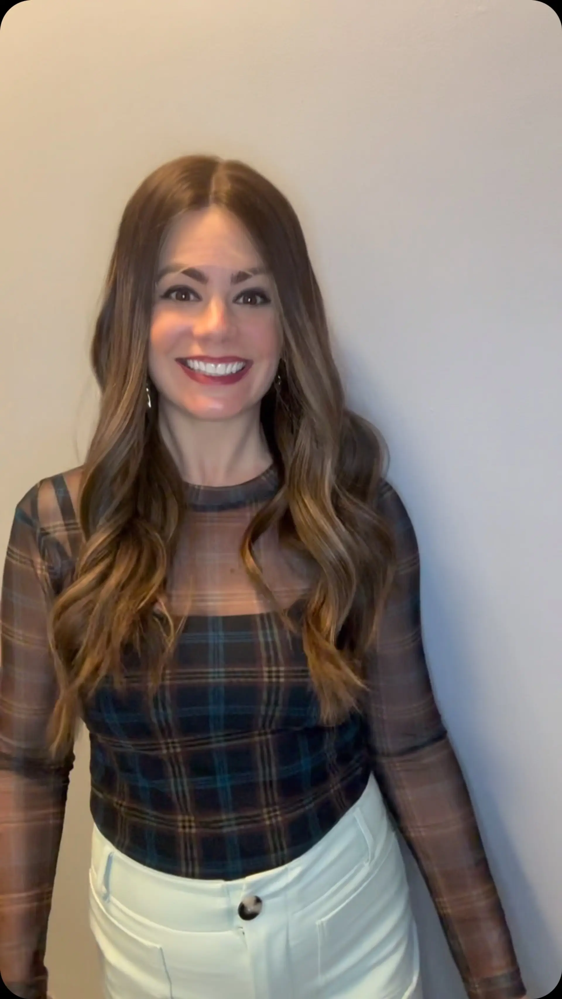 Long brown hair styled with loose, polished waves and a clean middle part. 1