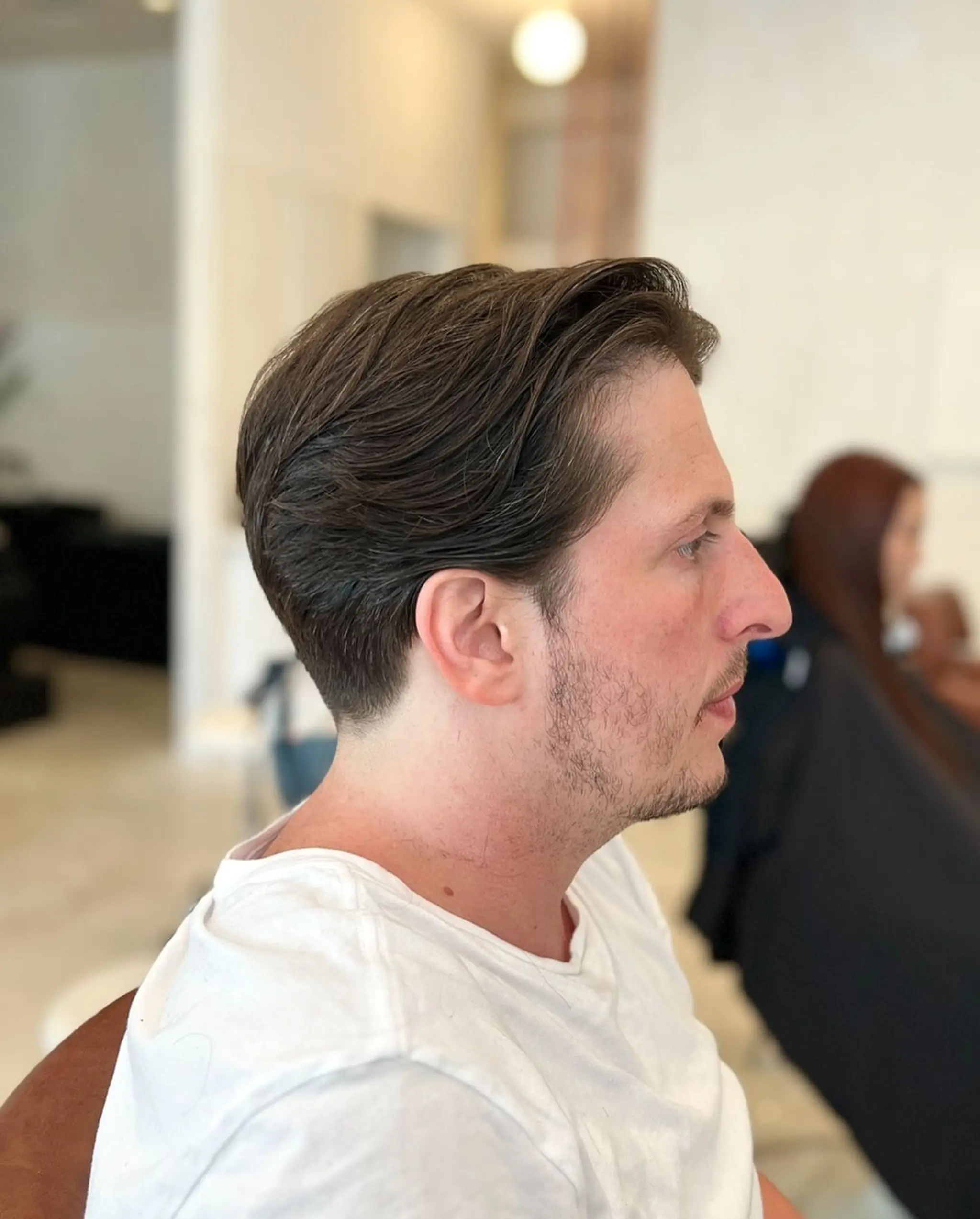 The 'Classic Side Sweep' features wavy, dark brown hair that is short in length, side-swept, and neatly tapered on the sides and back, giving a professional and sophisticated appearance.