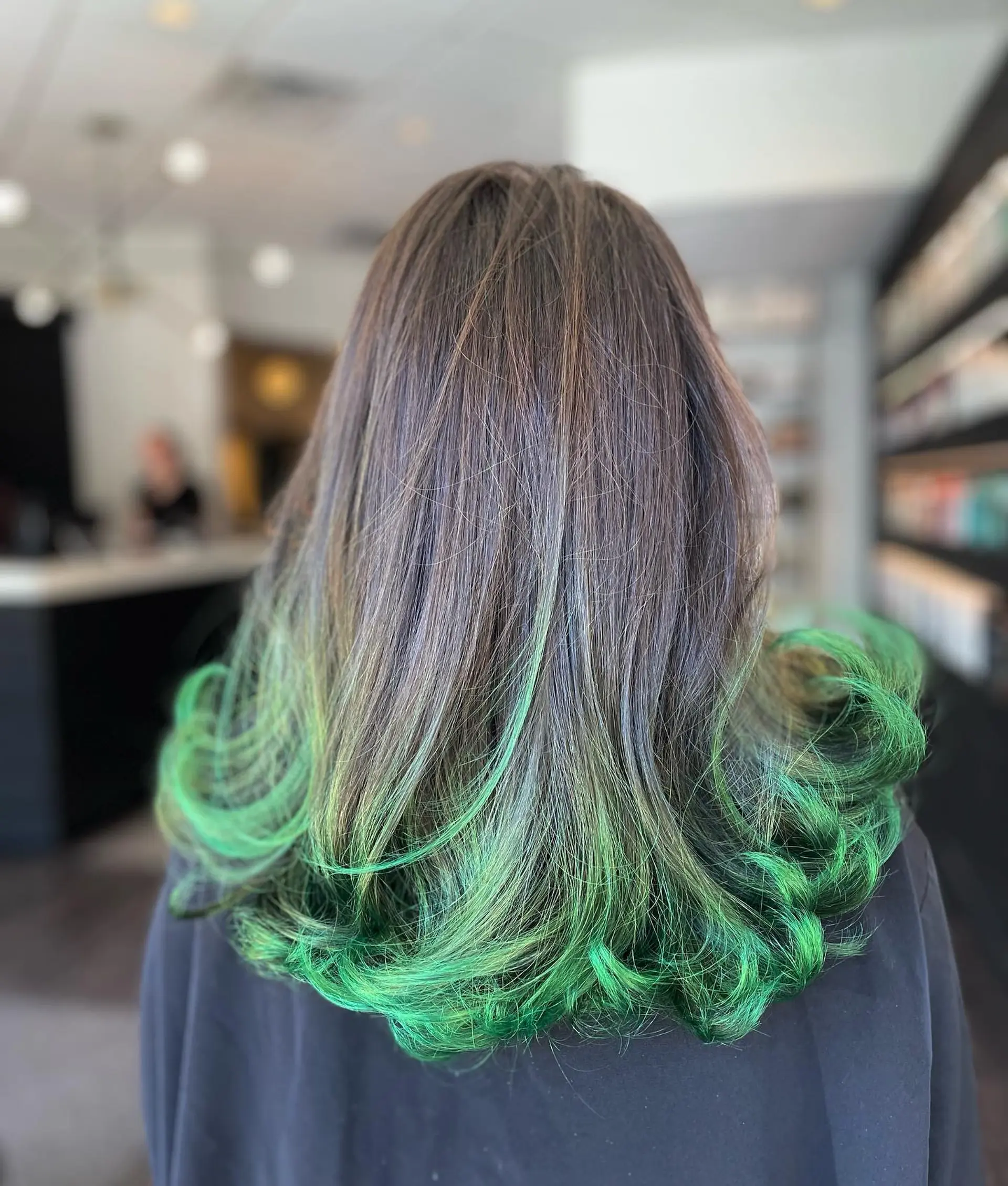 Medium-length dark brunette hair featuring vibrant vivid green dip-dyed ends styled into voluminous flipped curls. 1