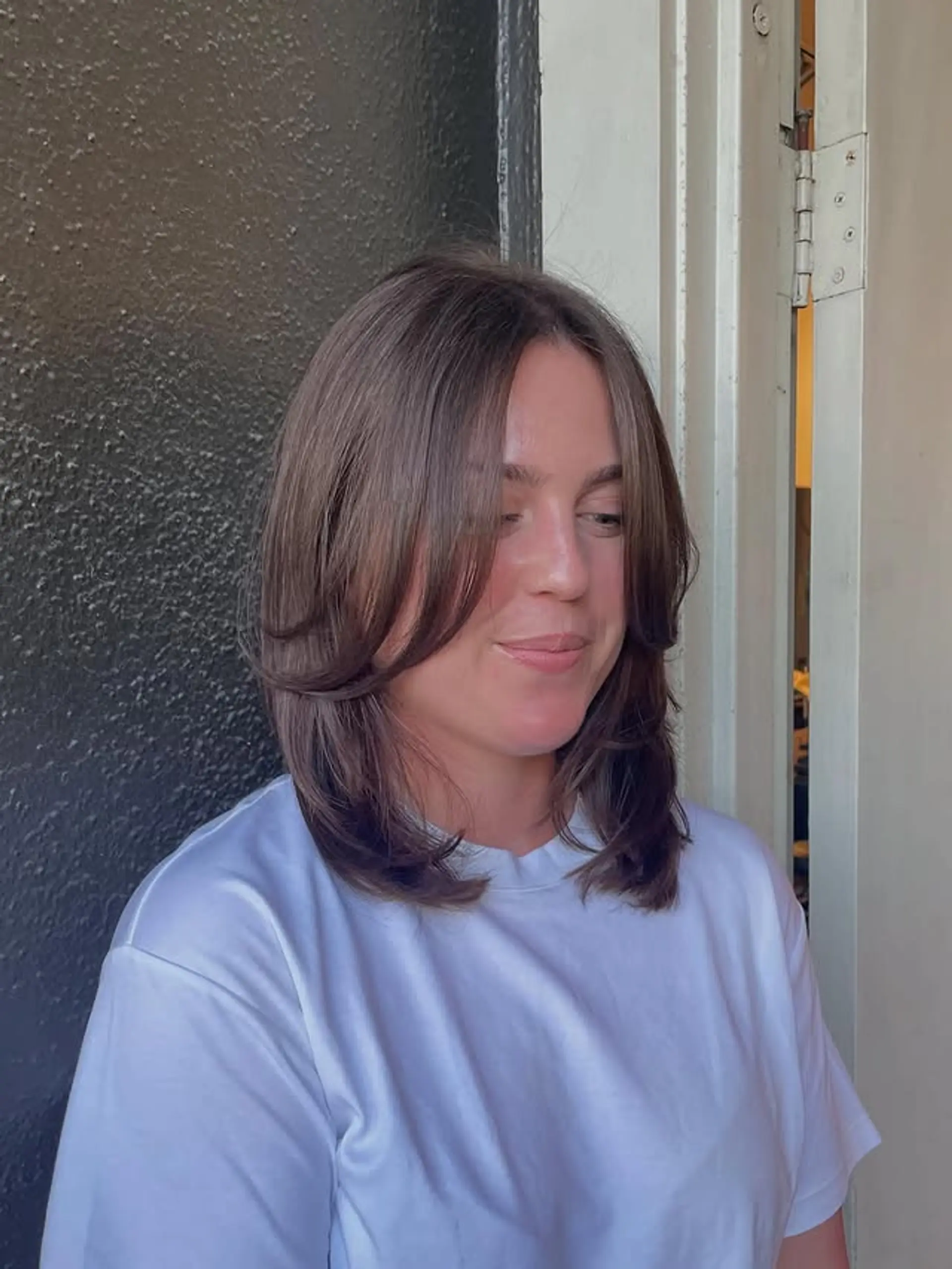 A medium-length layered hairstyle with face-framing curtain bangs. 1