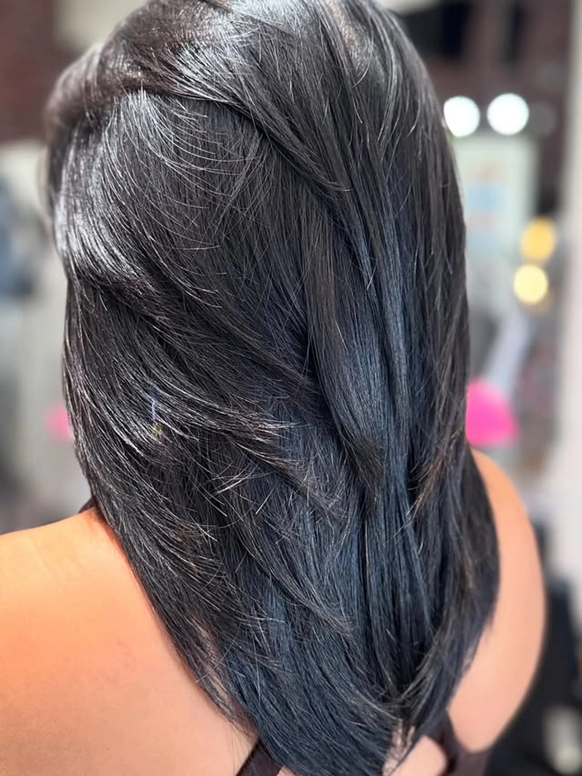 A sophisticated medium-length haircut characterized by soft, flowing layers that add volume and movement. The hair is styled sleek and smooth, with face-framing layers and a gentle curve at the ends. 1
