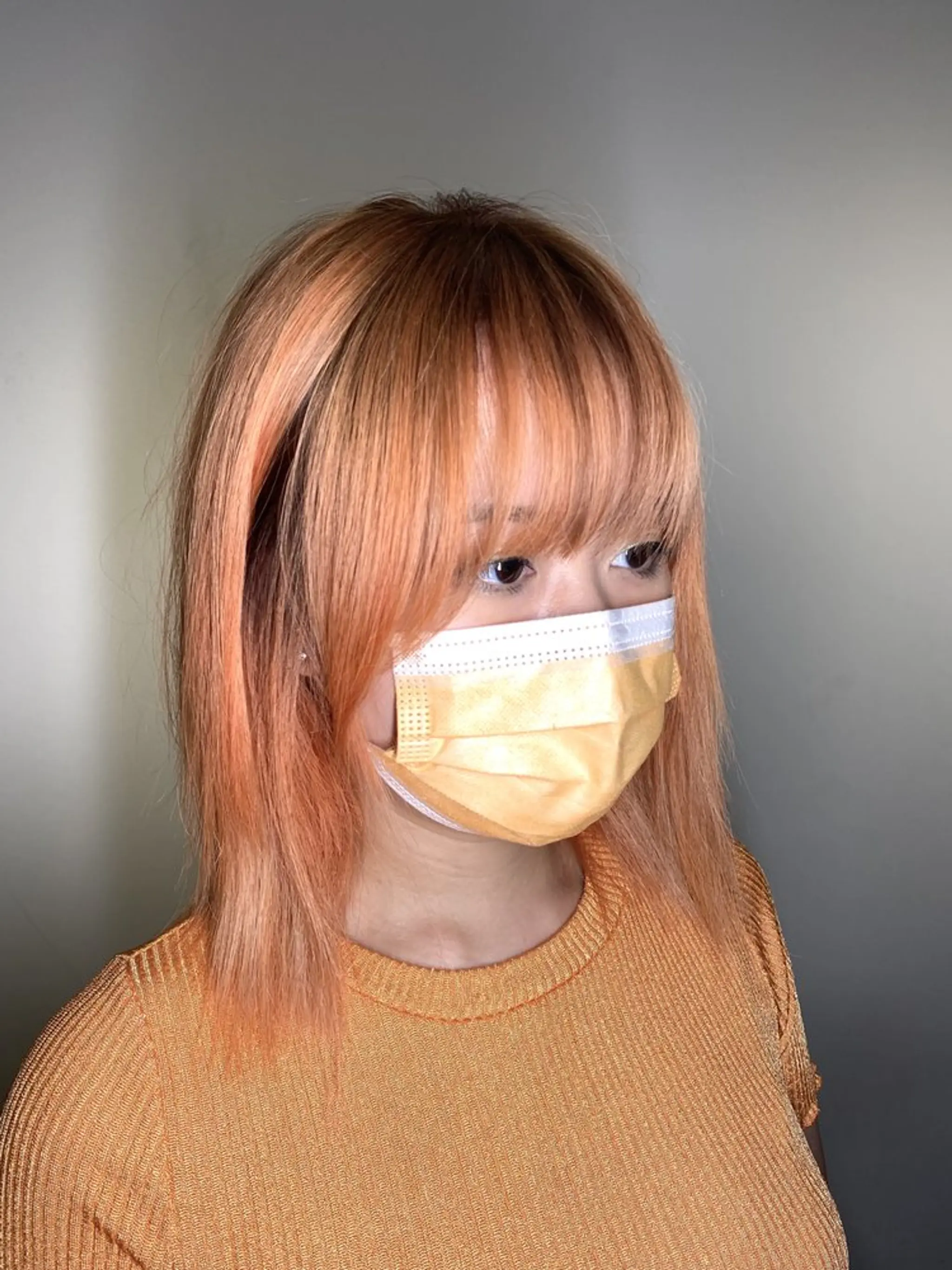 Straight, medium-length hair with a peach and orange two-tone color, featuring face-framing layers and a straight cut fringe.