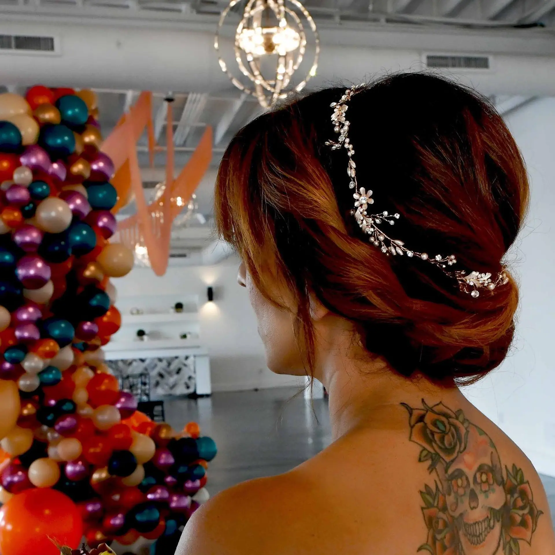 A romantic bridal low chignon featuring sweeping rolled sections accentuated by a sparkling floral and pearl hair vine. 1