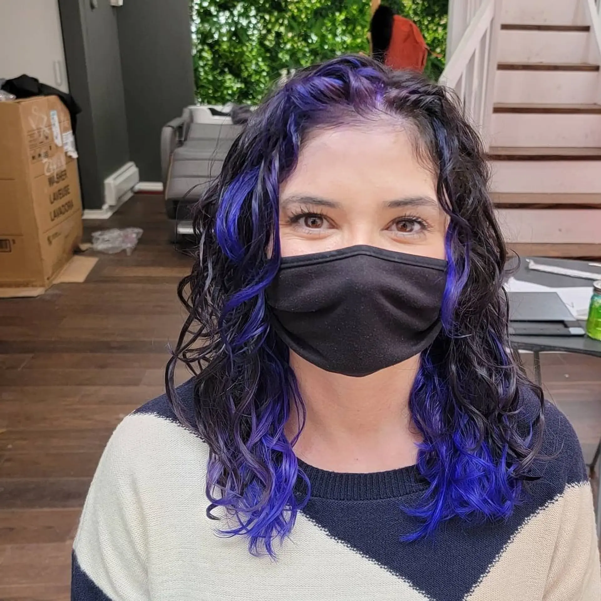 Medium length, curly hair with black base color highlighted by bold purples cascading through the curls and layered tips for added dimension. 1