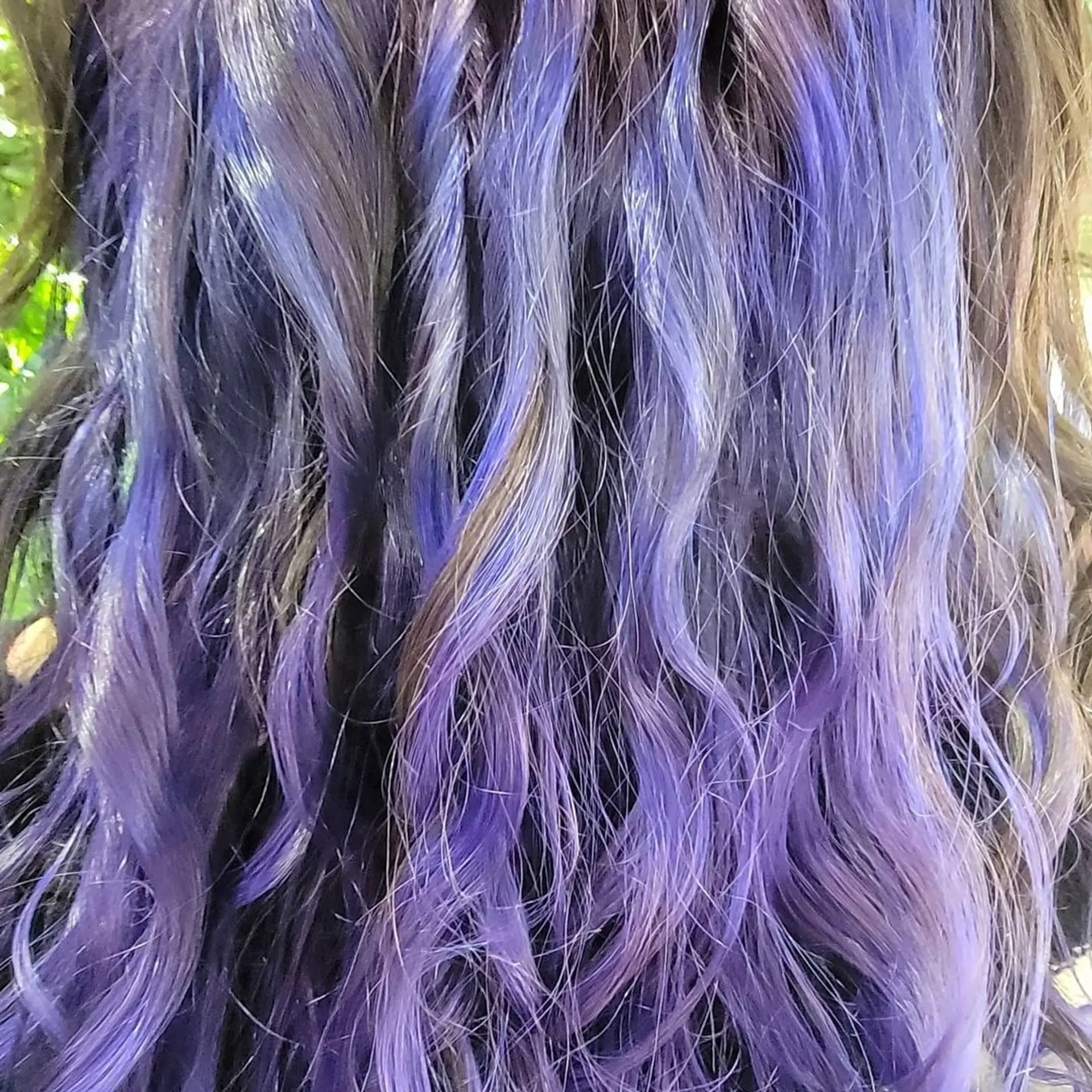 Medium length, curly hair with black base color highlighted by bold purples cascading through the curls and layered tips for added dimension. 2