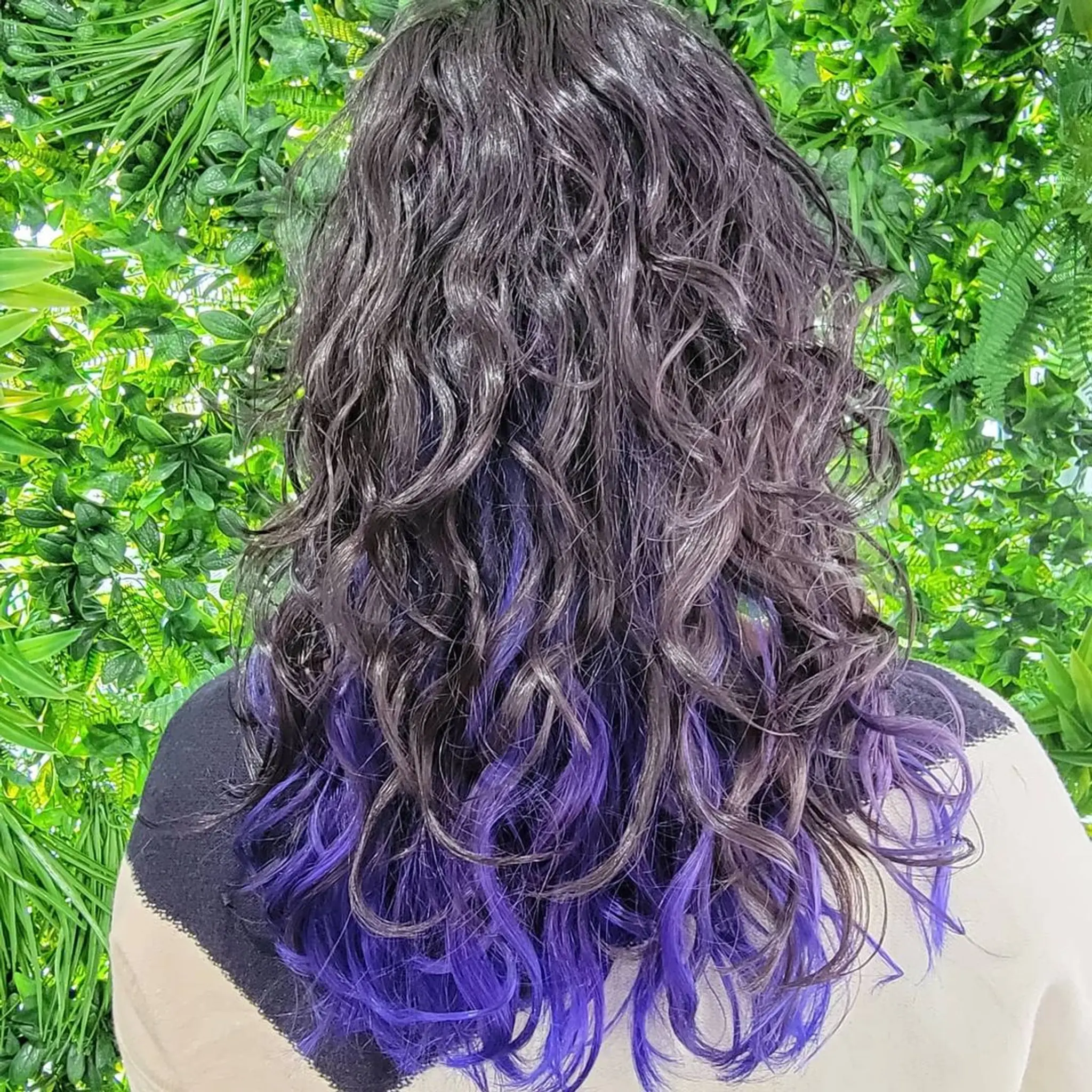 Medium length, curly hair with black base color highlighted by bold purples cascading through the curls and layered tips for added dimension. 3