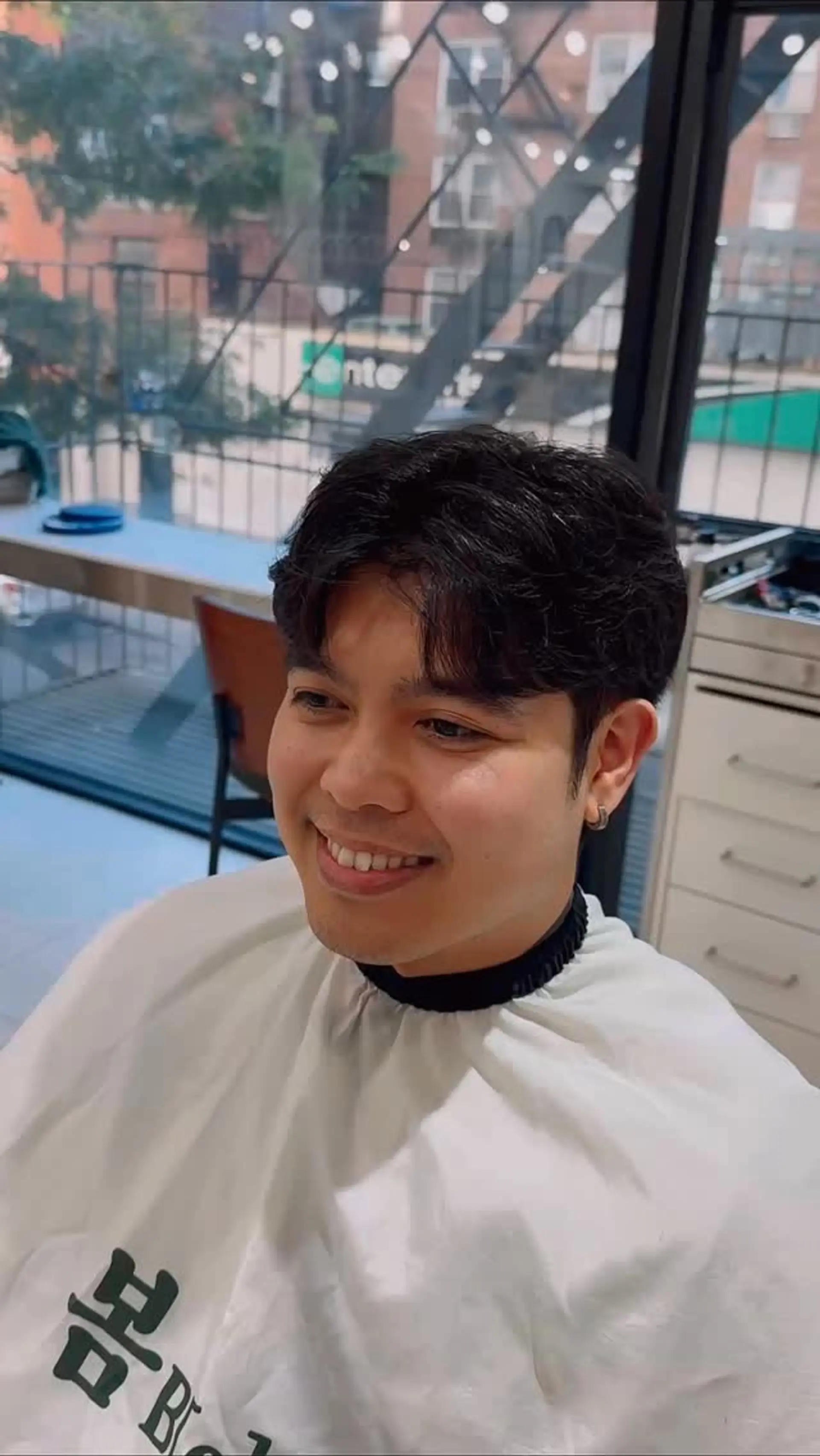 A men's short haircut styled with soft, natural waves and center-parted curtain fringe. 1