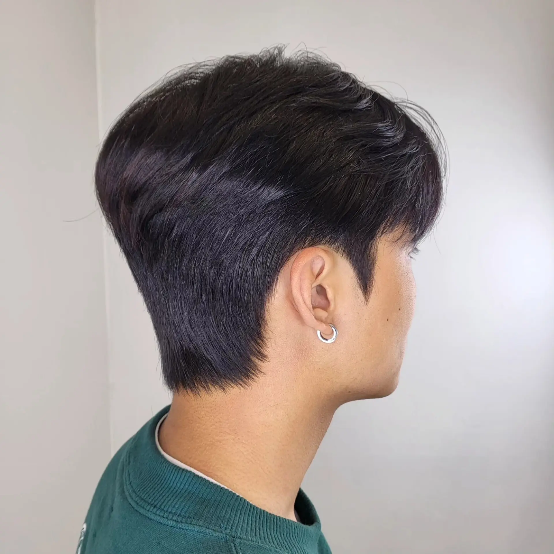 A modern short men's haircut featuring soft textured layers on top, tapered sides around the ears, and a clean, contoured nape. 1