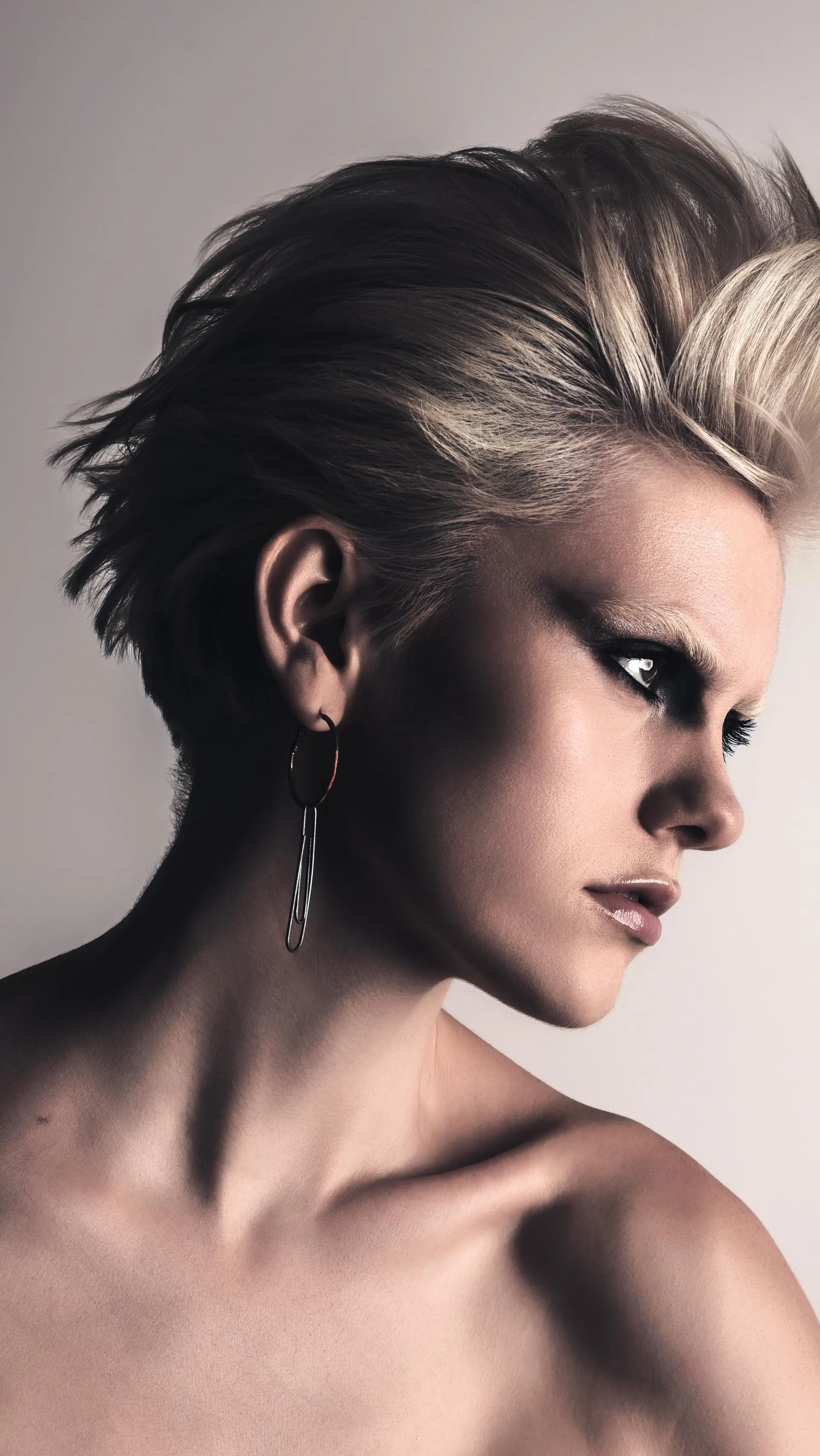 A styled short pixie cut with brushed-up textured volume on top in a bright platinum blonde shade. 1