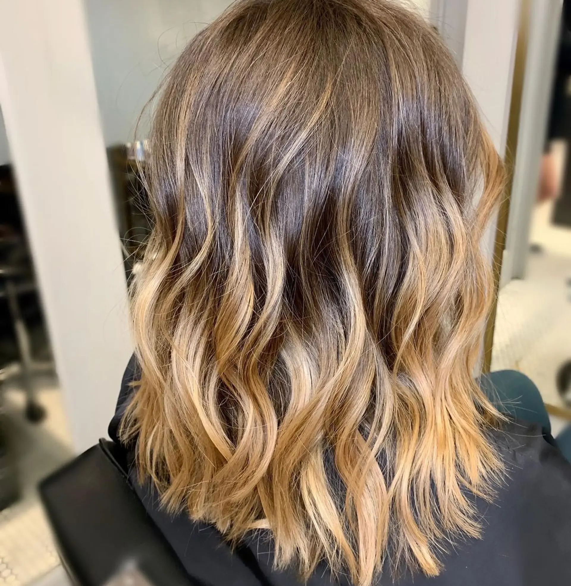 Medium-length wavy hair with a dark brown to honey blonde ombre and golden blonde tips, featuring a balayage style. 1