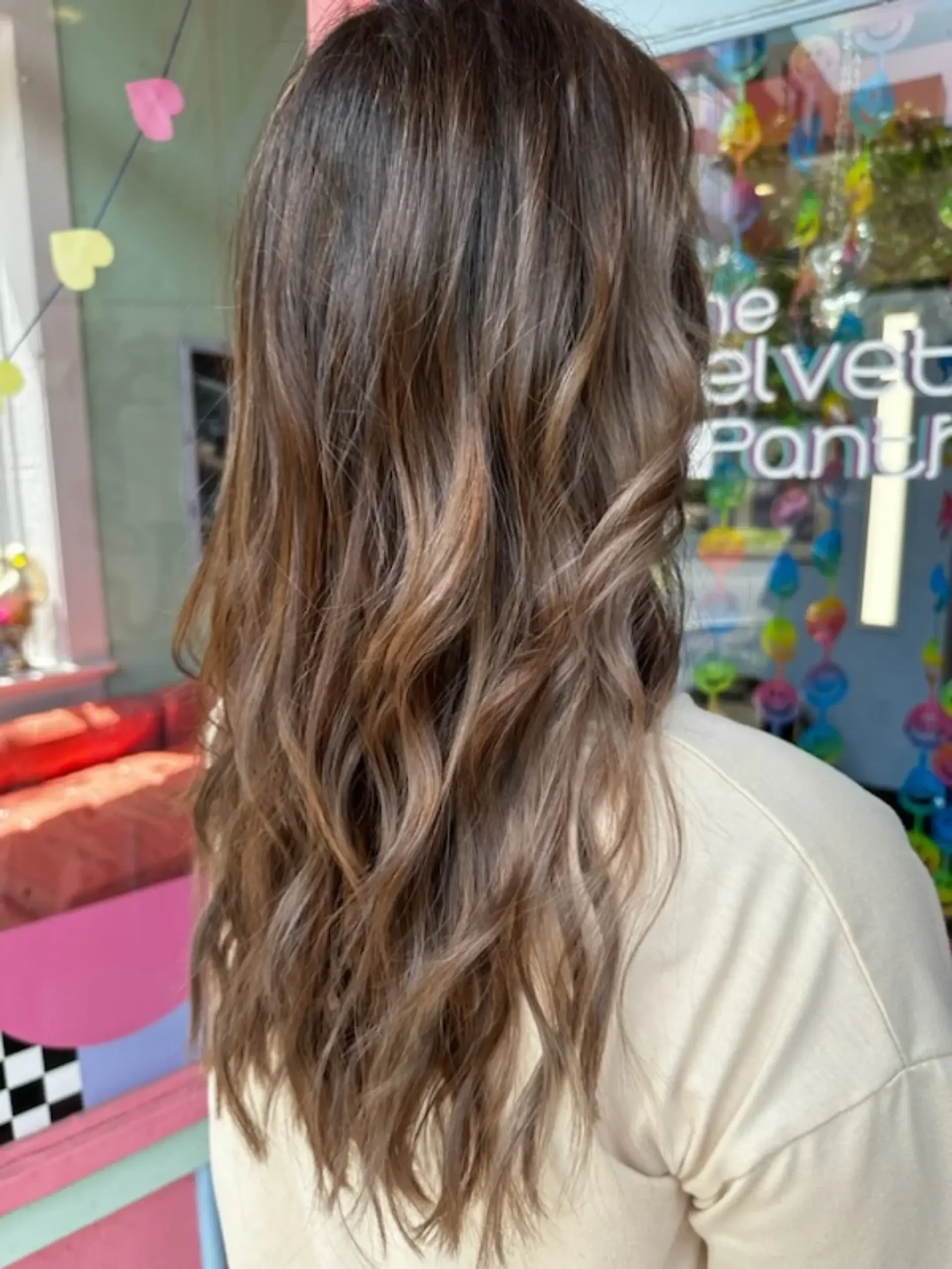 Long dimensional brunette hair styled in soft, loose waves with subtle caramel balayage highlights. 1