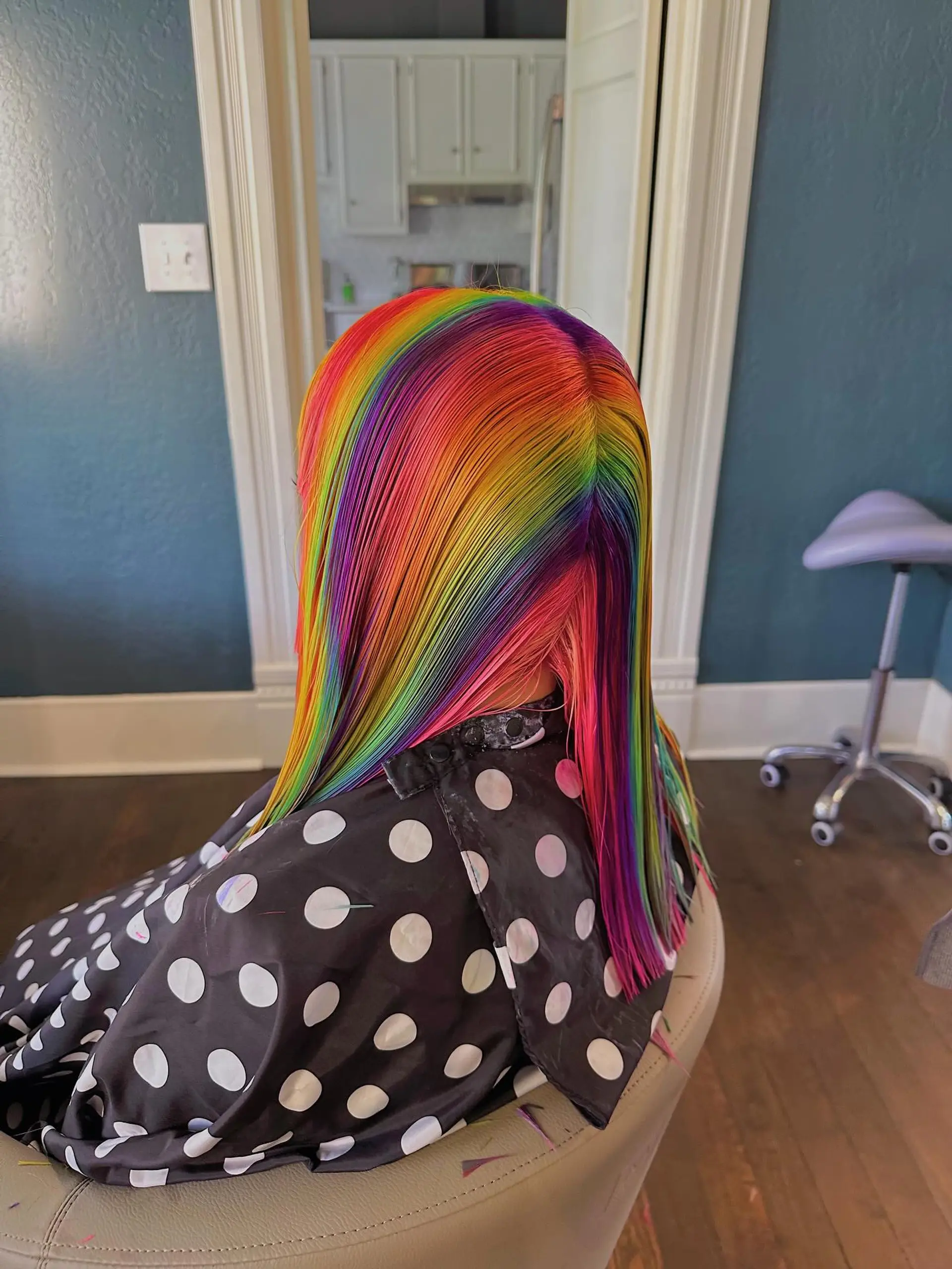 A medium-length hairstyle with vibrant rainbow coloring, characterized by sharp blunt bangs and soft face-framing layers that create a contemporary shag silhouette. 3
