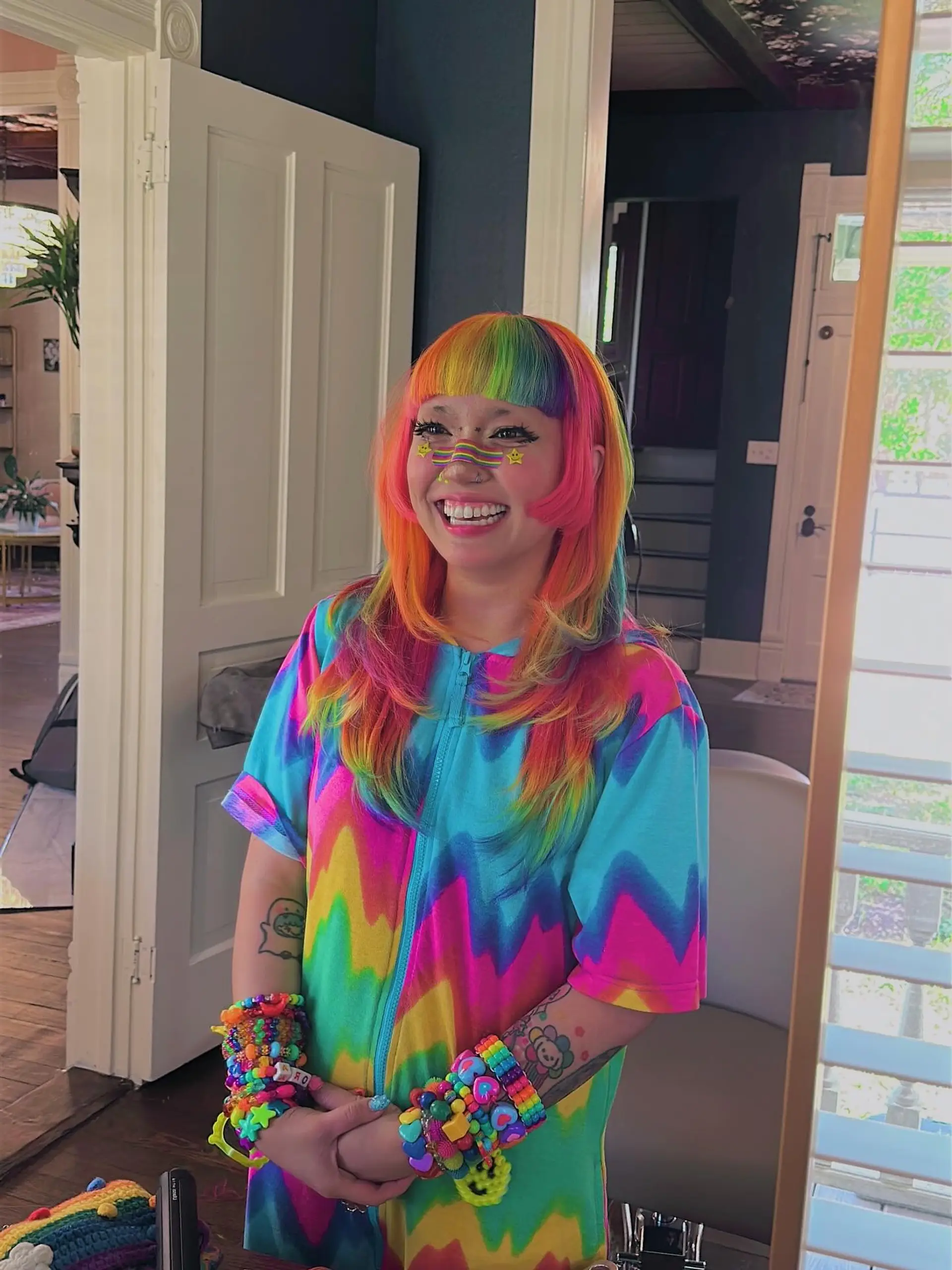 A medium-length hairstyle with vibrant rainbow coloring, characterized by sharp blunt bangs and soft face-framing layers that create a contemporary shag silhouette. 4