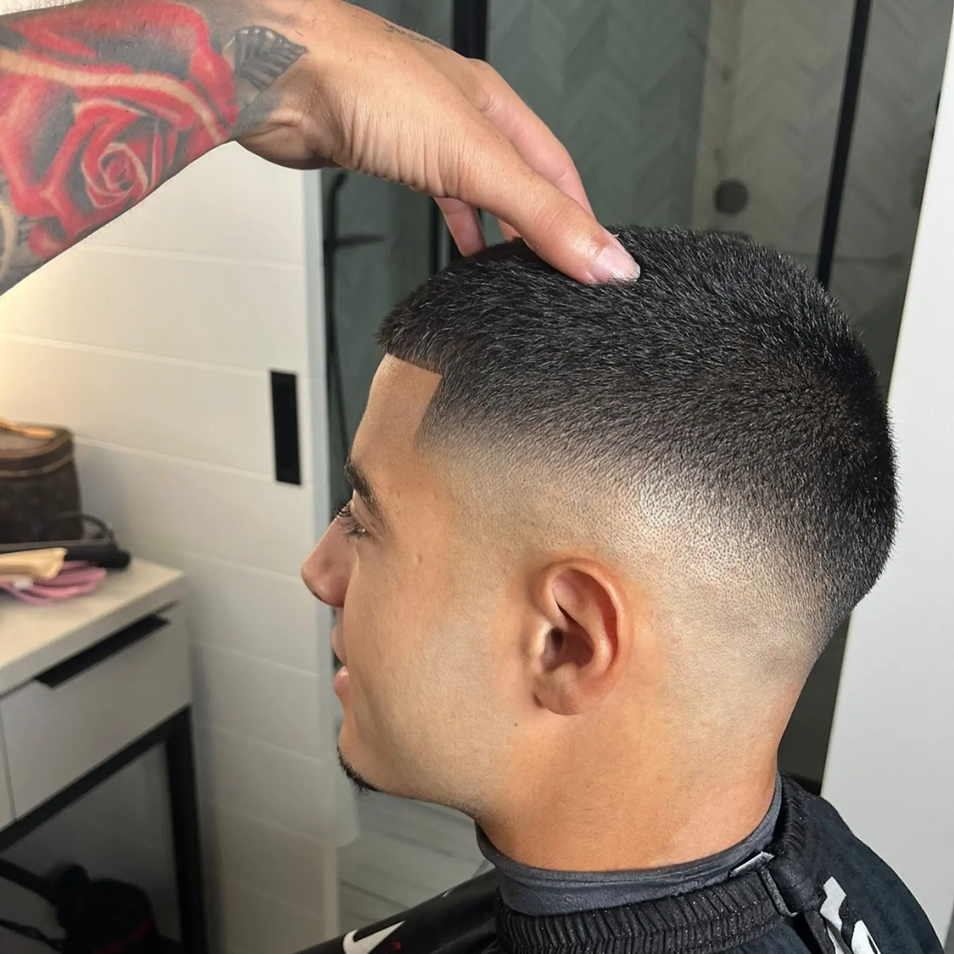 A sharp buzz cut on top transitioning into a smooth mid skin fade with a crisp edge up. 1