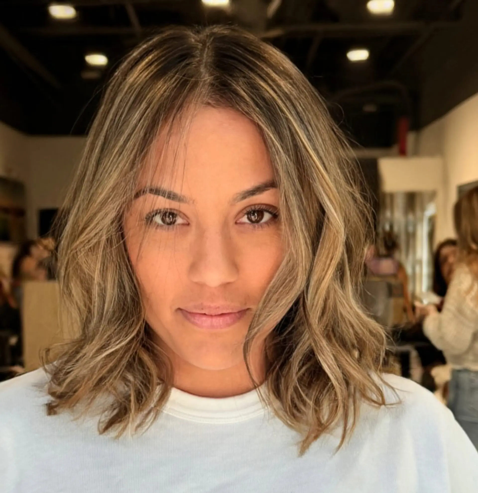 A textured shoulder-length lob styled with loose, relaxed waves and a center part. 1