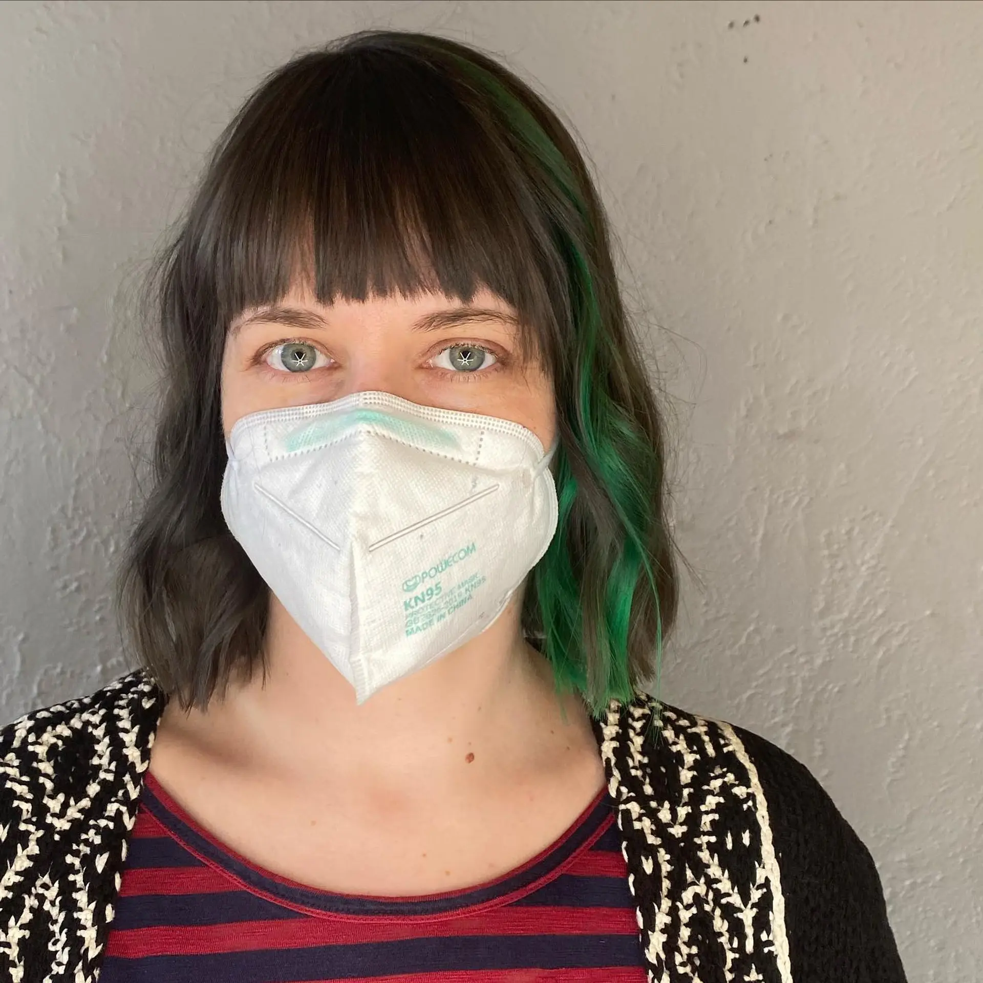 A chic blunt bob with straight bangs and eye-catching vivid green highlights. 1