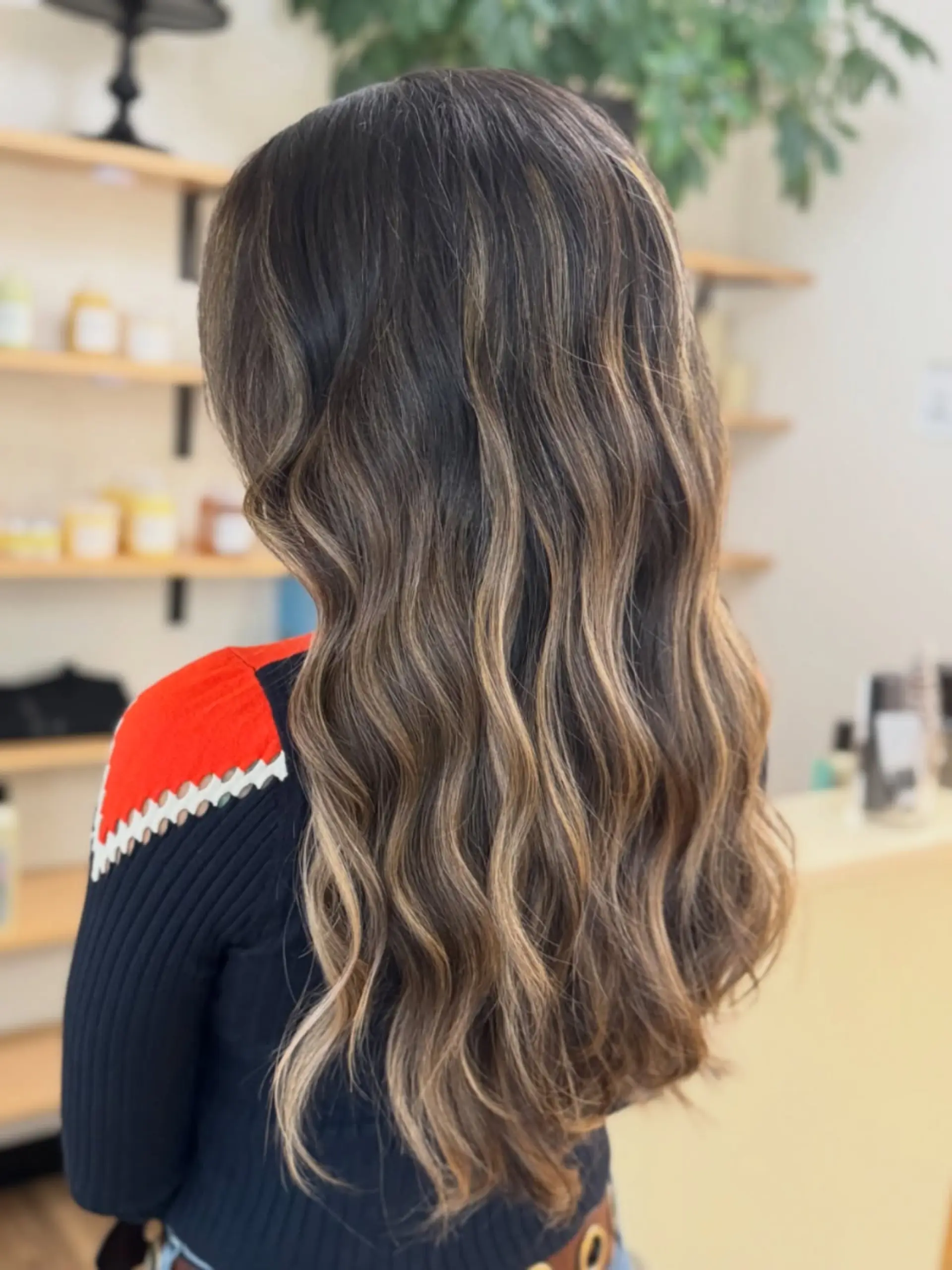 Long, flowing dark brunette hair enhanced with seamless caramel and honey blonde balayage highlights, styled in loose, soft waves. 1