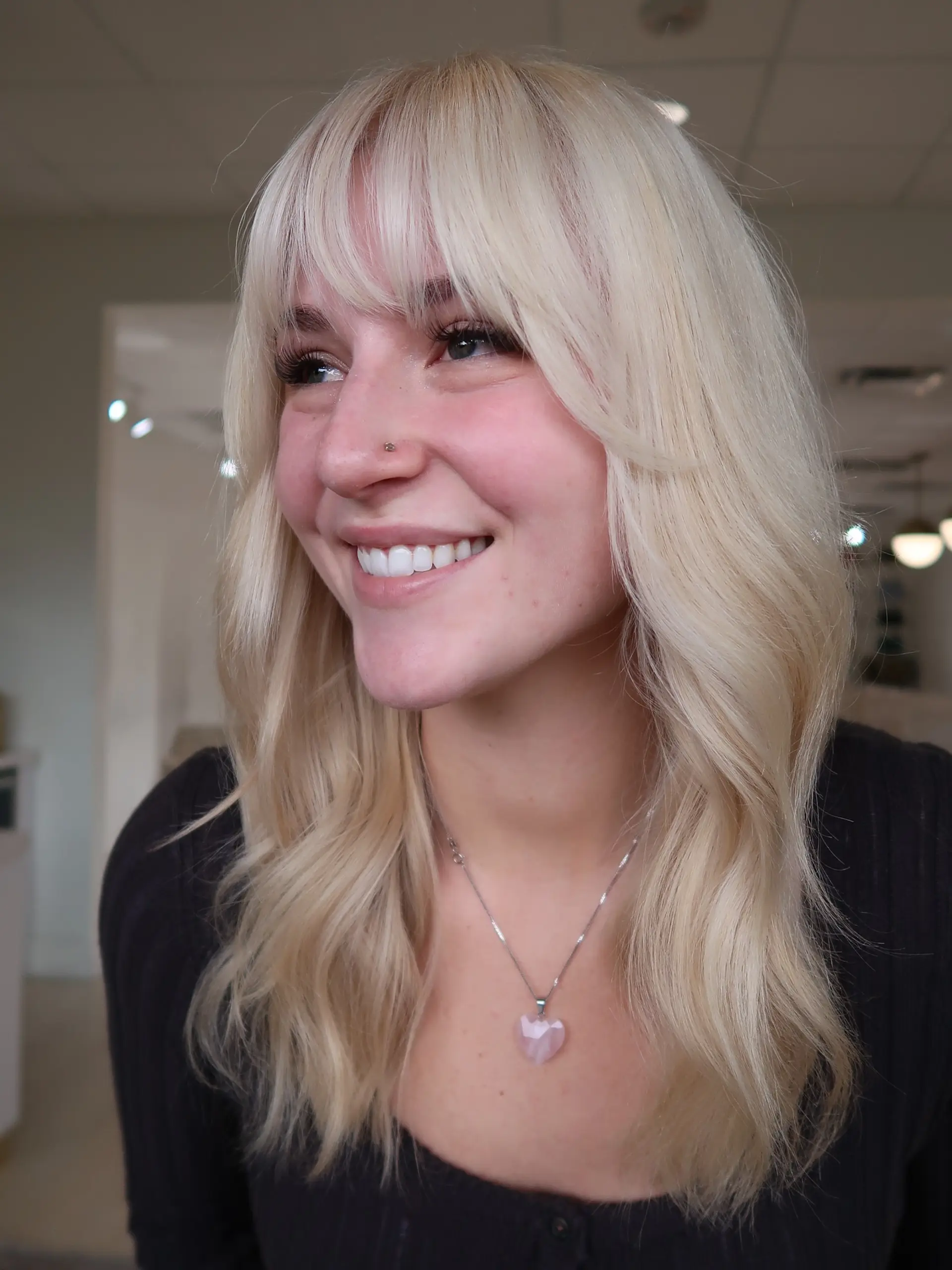 Bright platinum blonde medium-length hair styled in soft waves with face-framing wispy bangs. 1
