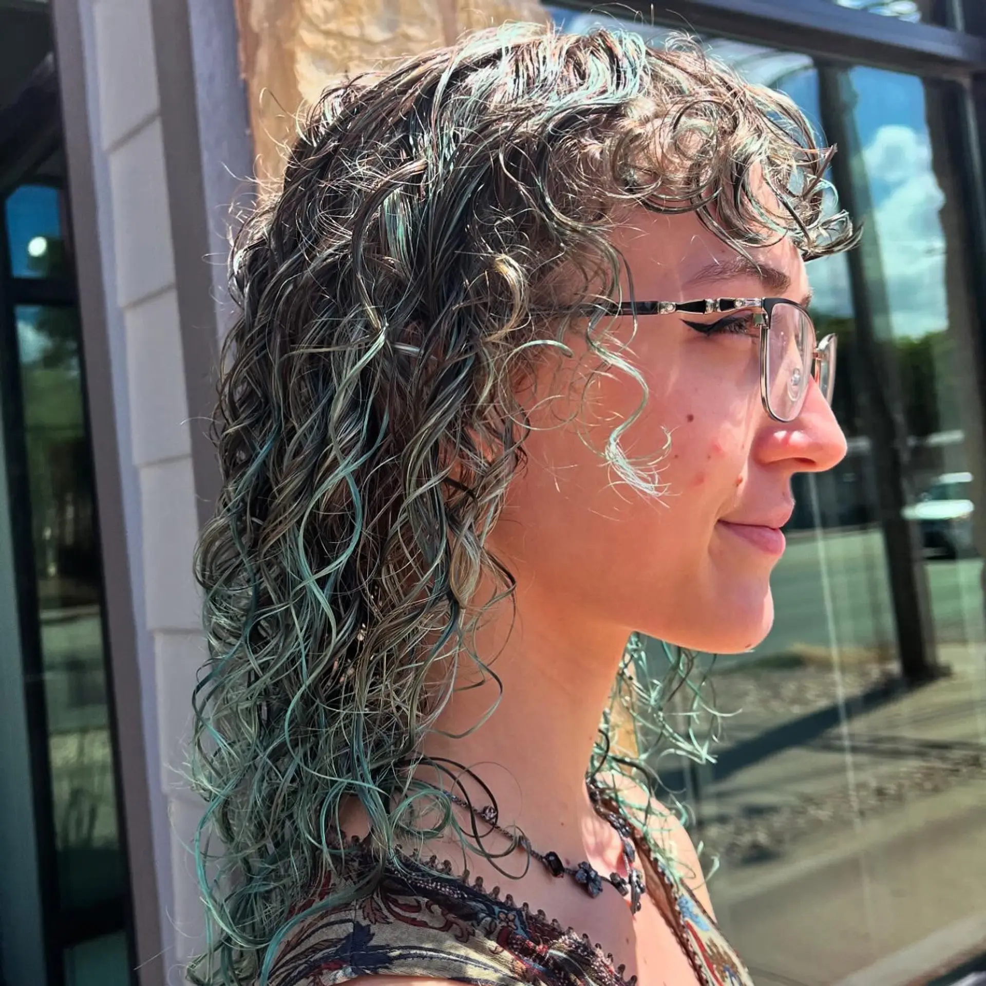 Shoulder-length defined curls featuring curly fringe bangs and pastel teal highlights. 1