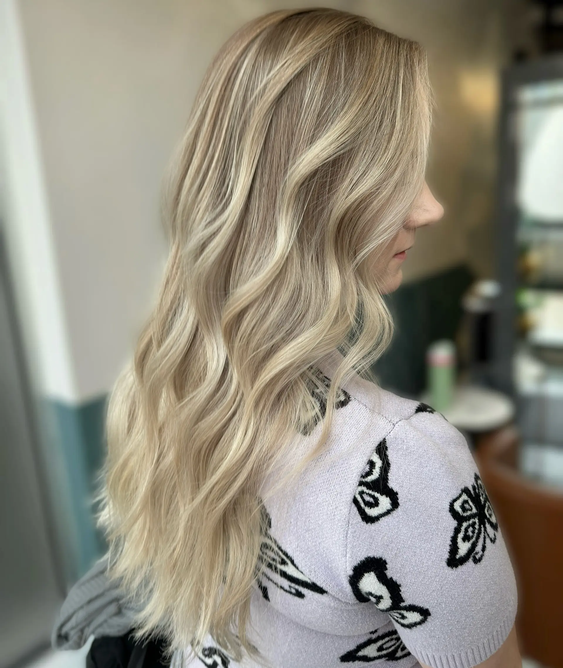 Long, layered wavy hairstyle with a balayage blonde color. 1