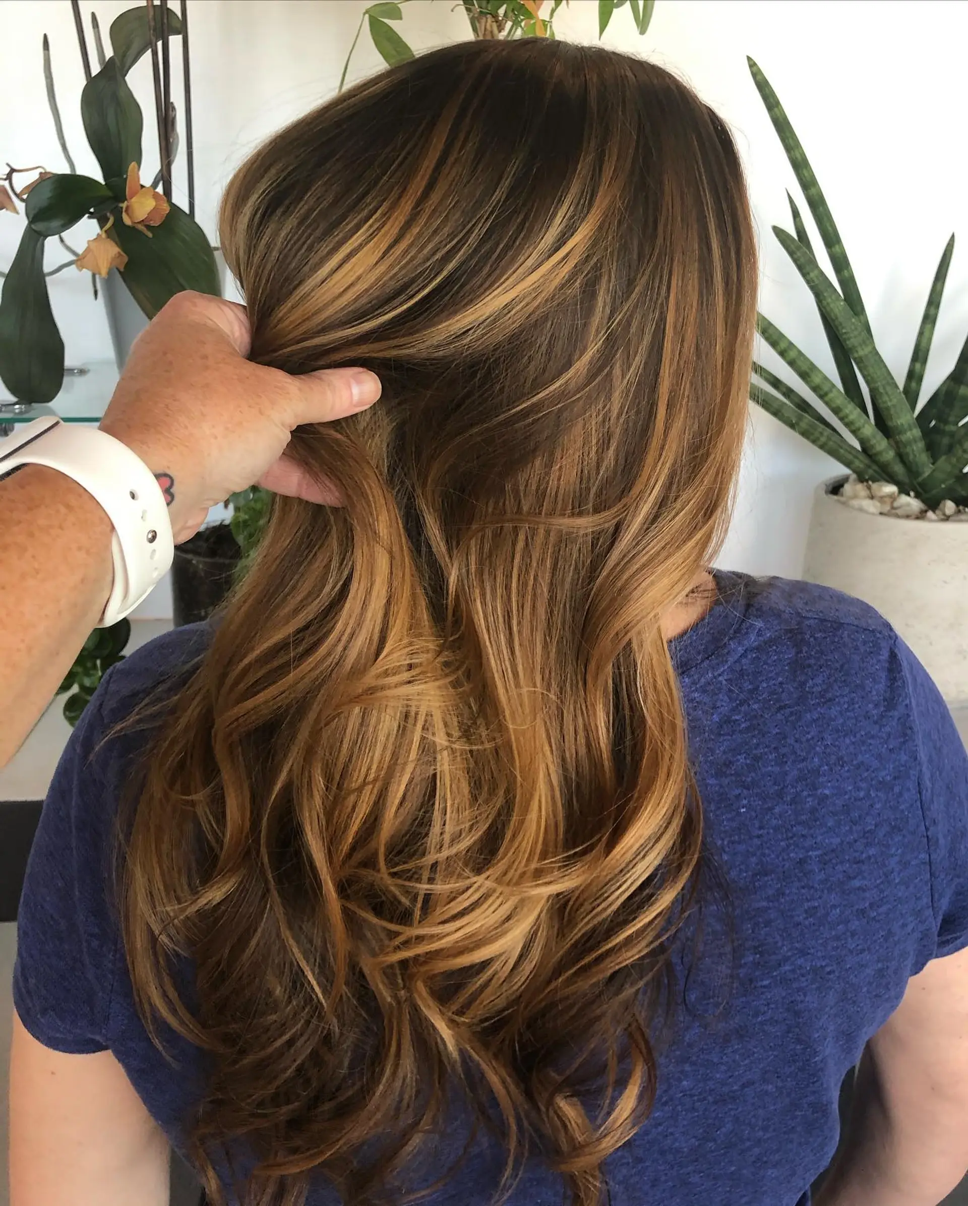 Long dimensional balayage featuring rich caramel and honey blonde ribbons blended through a warm brown base, finished with soft waves. 1