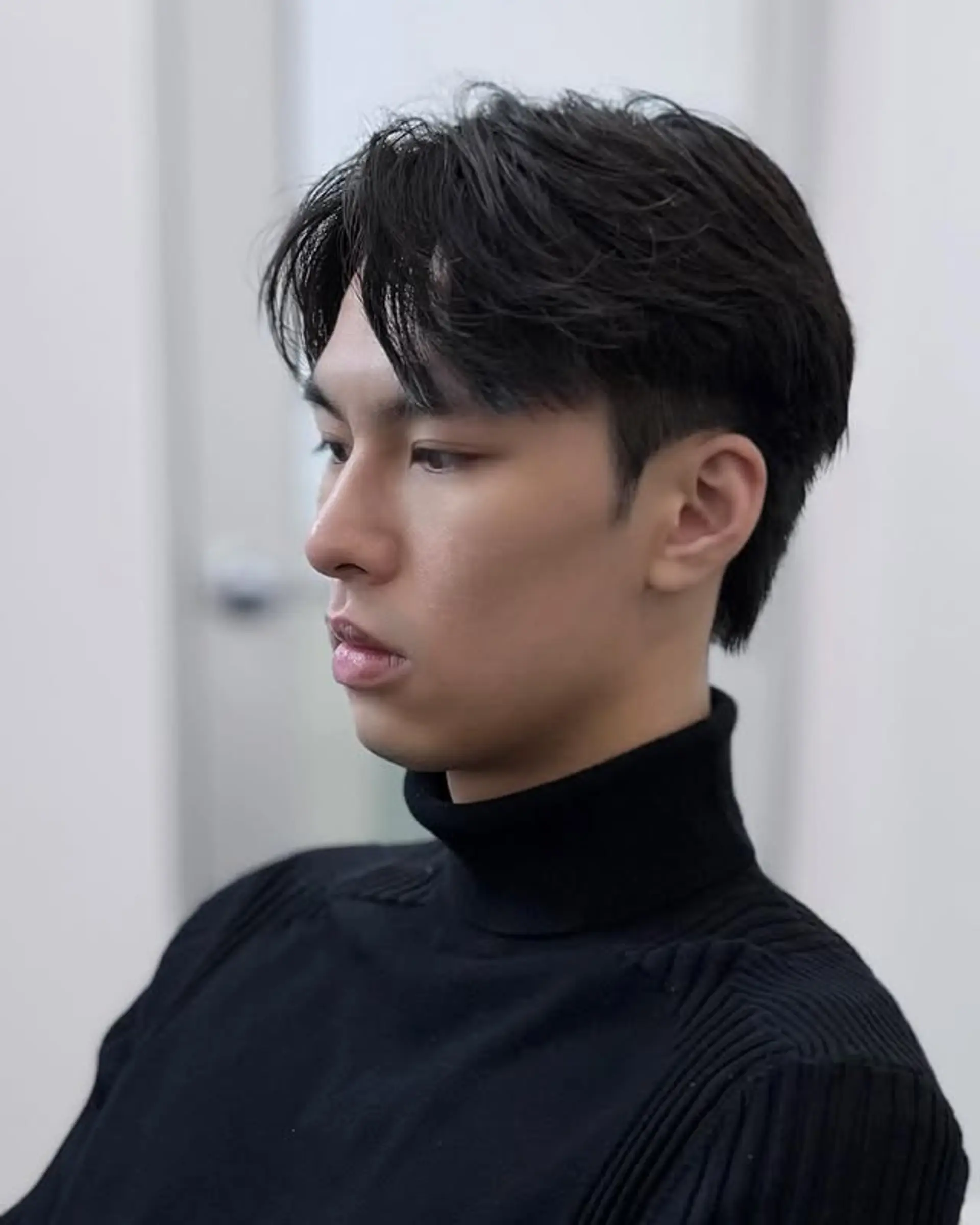 A modern two-block cut for men, showcasing a textured, slightly wavy top that flows into tapered sides and a soft, longer back for a contemporary and stylish silhouette. 1