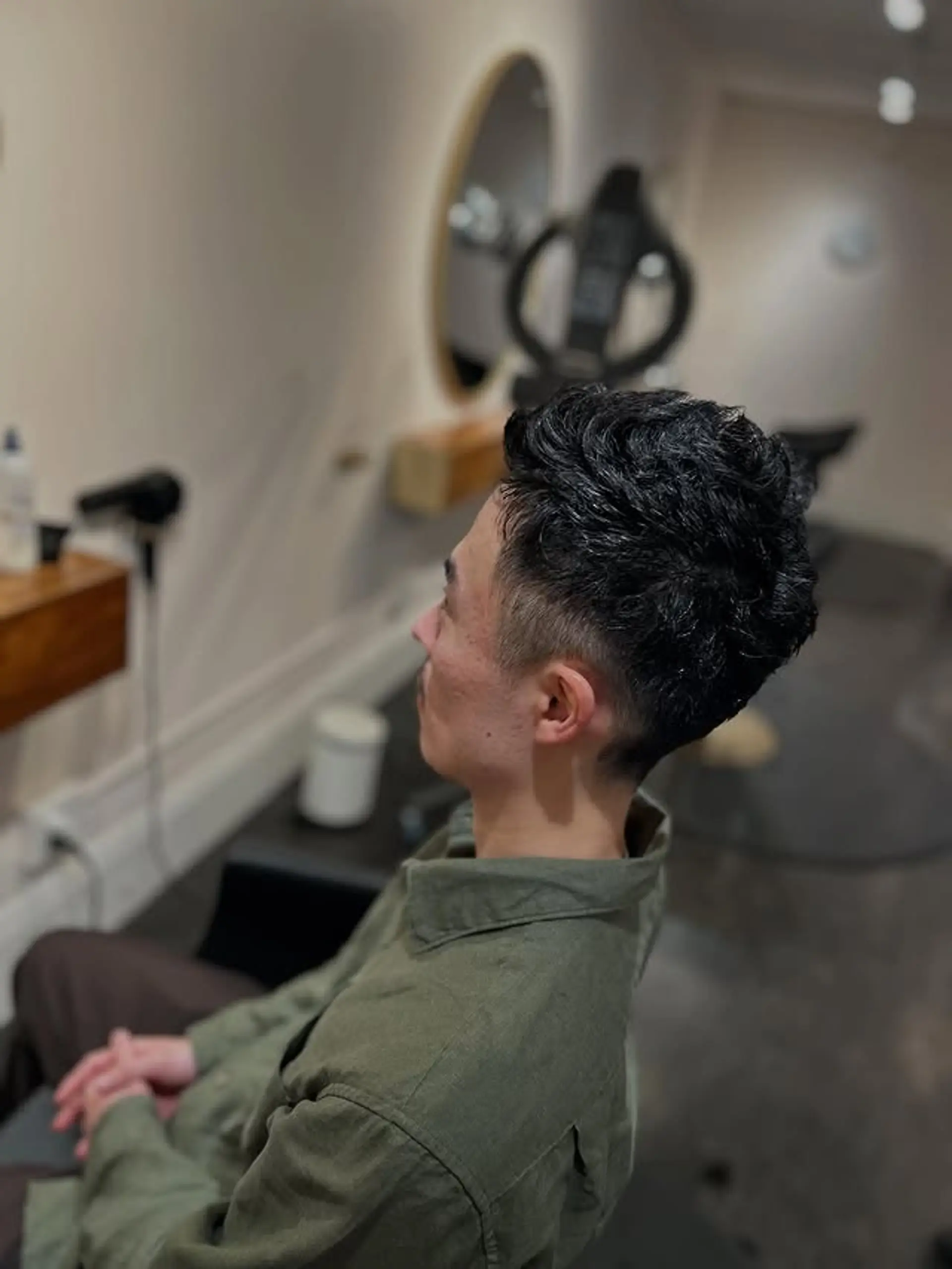 This stylish men's haircut features a short, textured wavy top that provides volume and movement, complemented by a clean and sharp low fade on the sides and back. 1