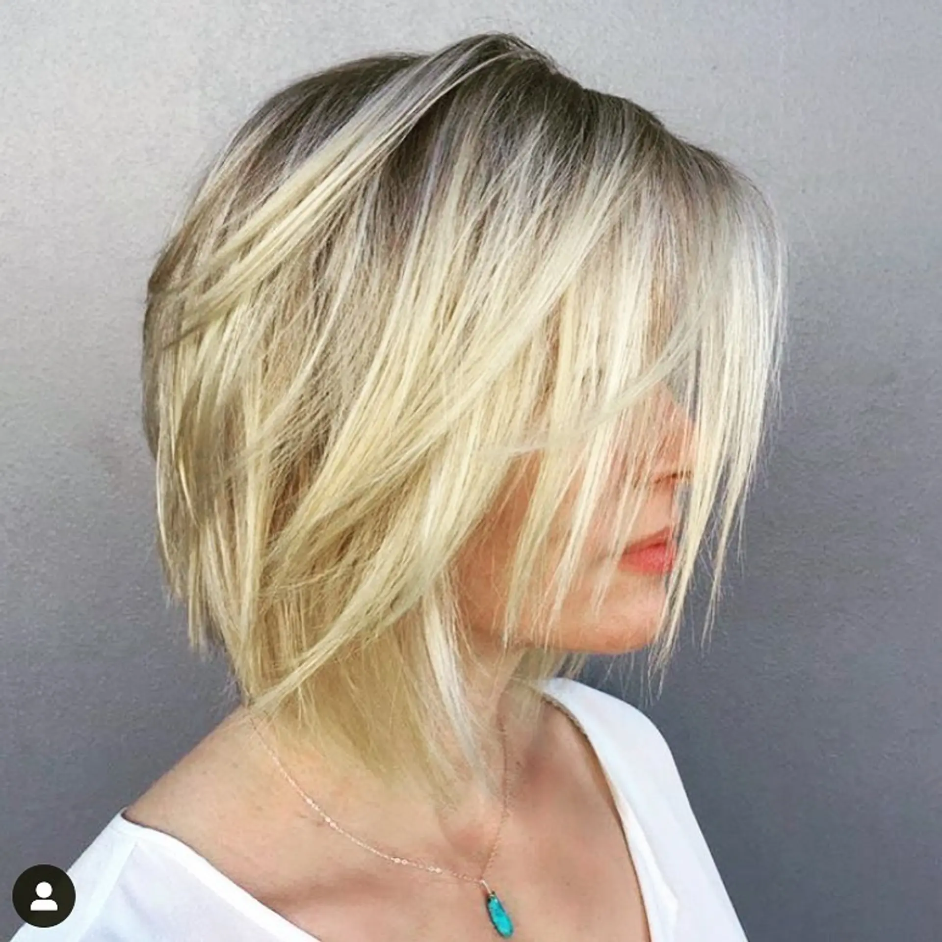 A textured blonde shaggy bob haircut featuring piecey layers and subtle root depth. 1