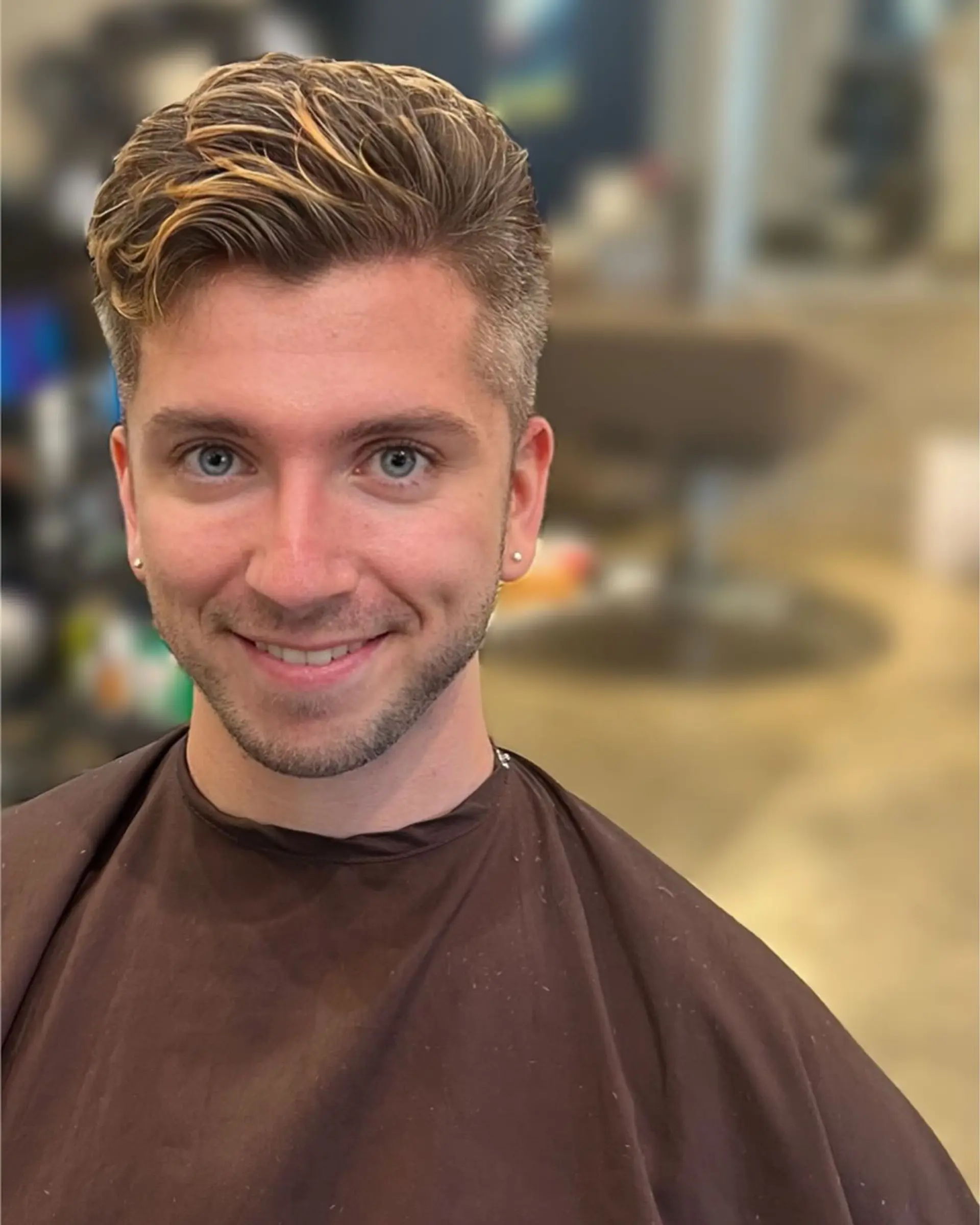 A men's short tapered cut styled upward and back with textured blonde highlights through the top. 1