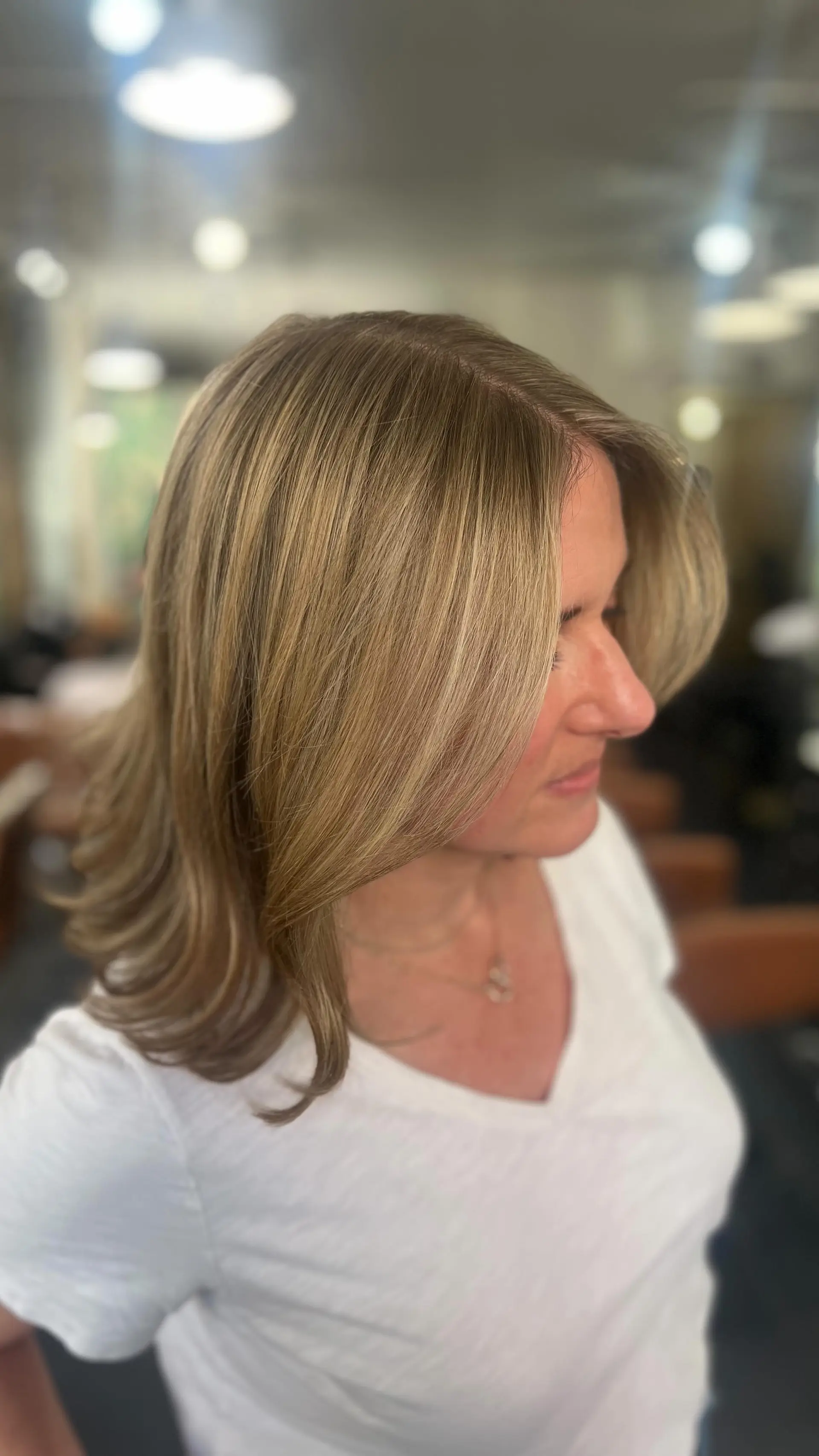 Medium-length hair featuring finely blended warm blonde highlights, styled into a smooth blowout with flipped ends. 1