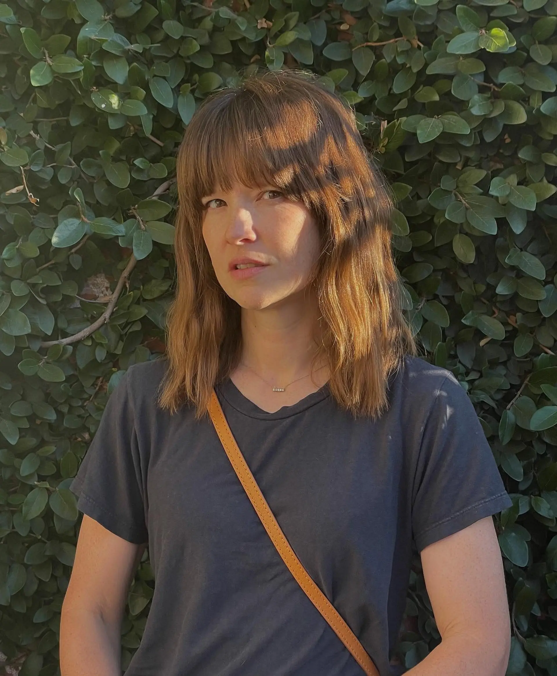 A textured medium-length haircut featuring full front bangs and subtle soft movement in warm golden brown tones. 1