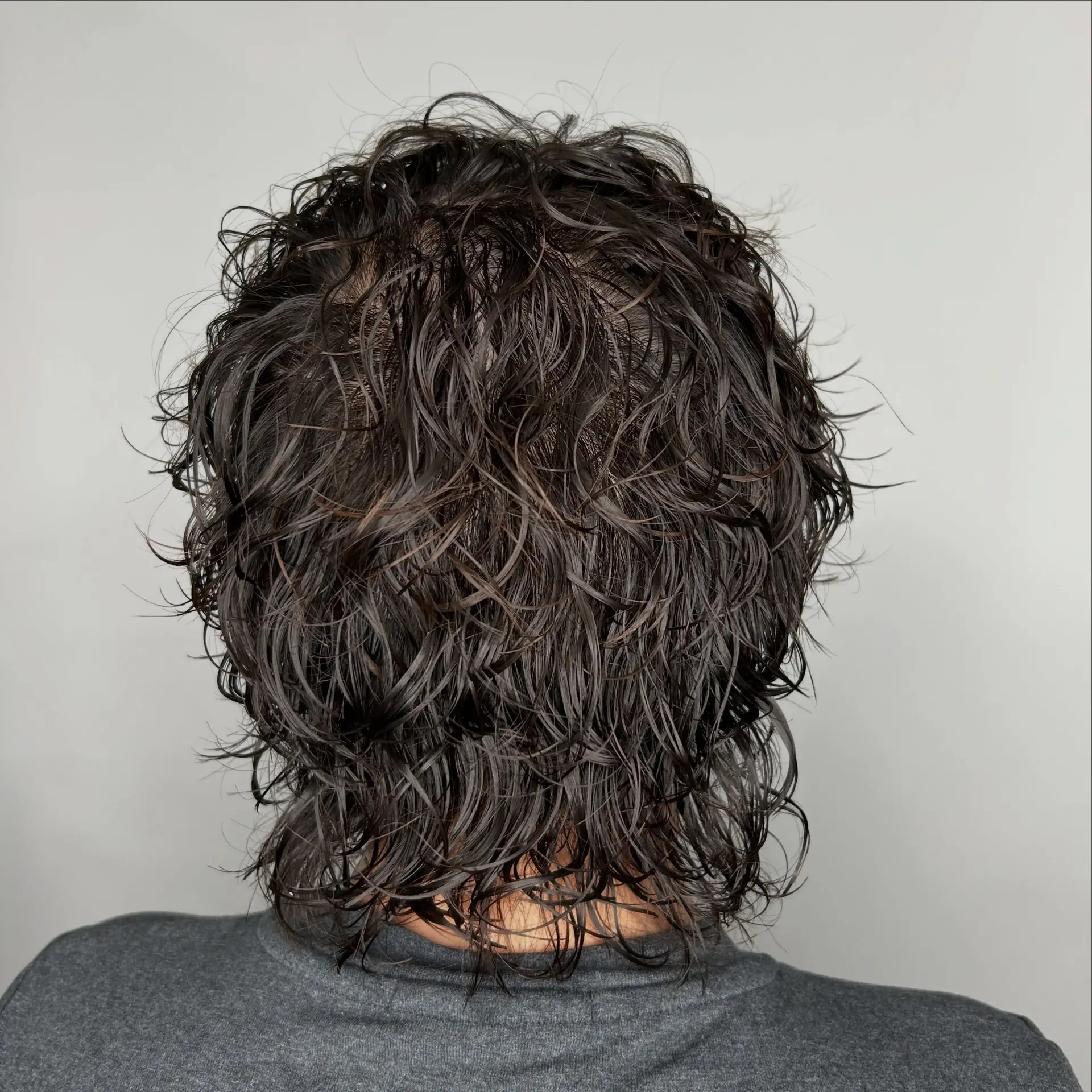 A textured, piecey perm styled wet with defined waves cascading down to the nape of the neck. 1