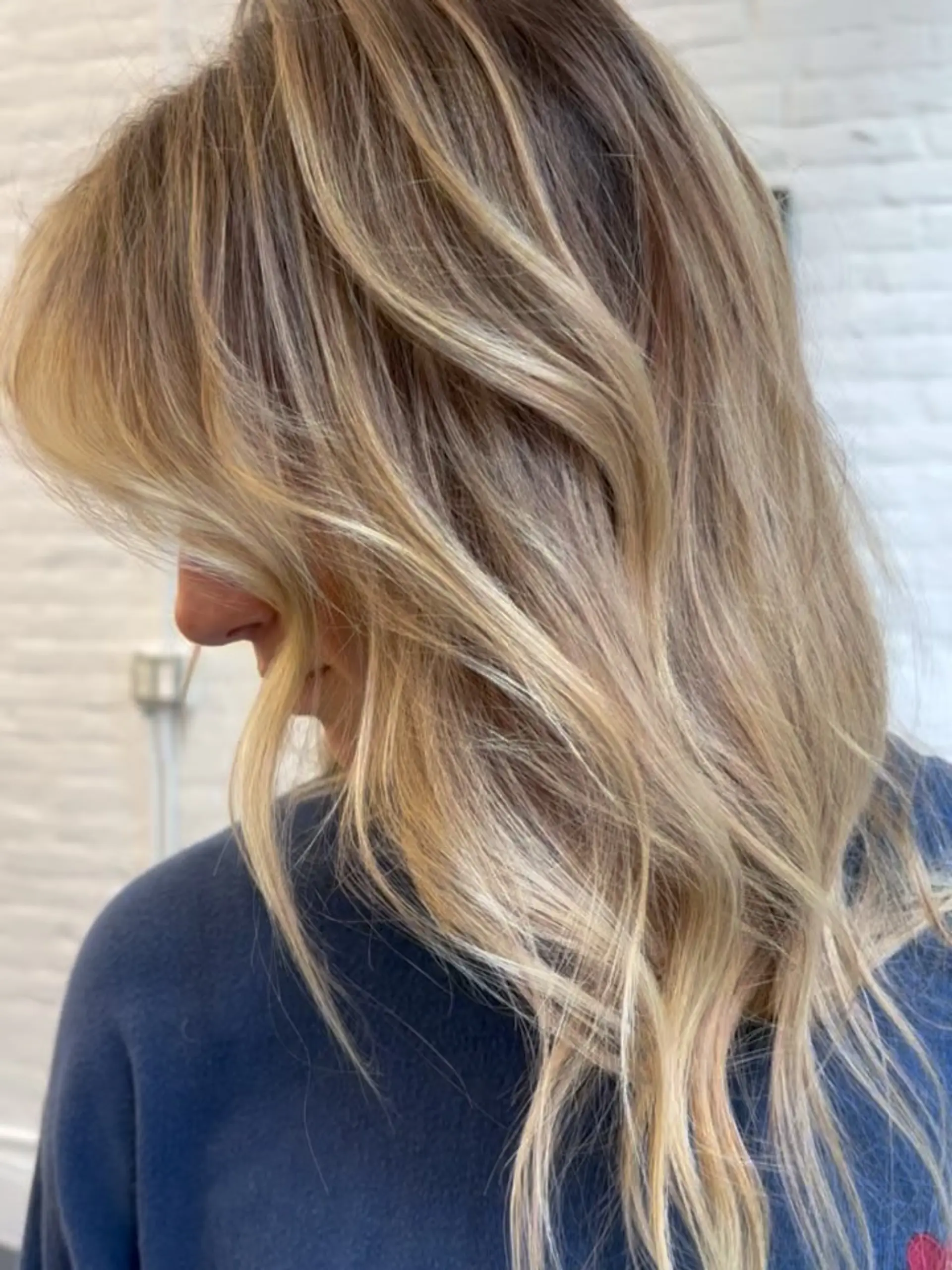 A dimensional blonde balayage with a natural shadow root styled into soft, beachy waves. 1