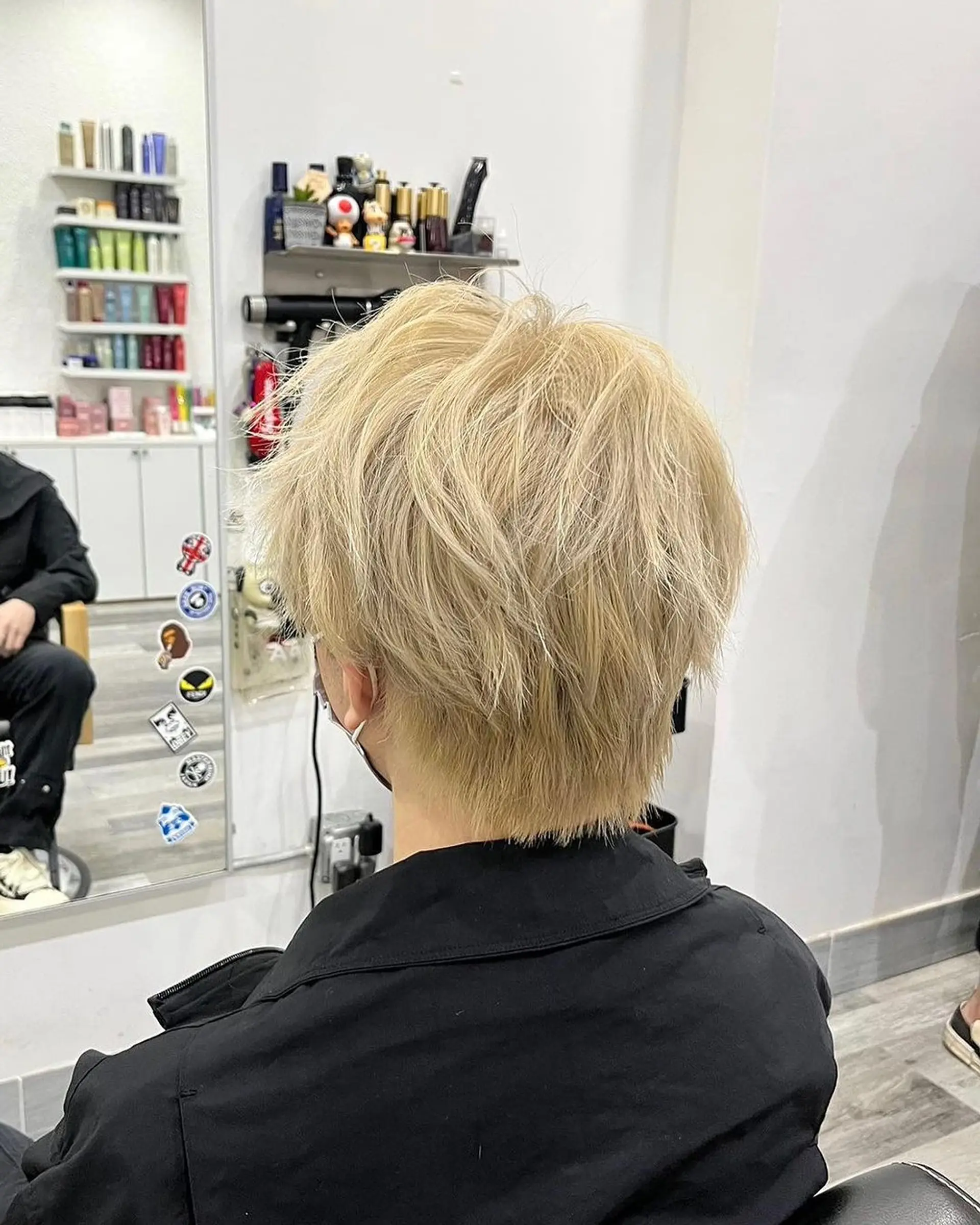 A medium-length wavy cut with a tousled, layered texture in a striking blonde shade, featuring a side part for a natural, effortless look. 3