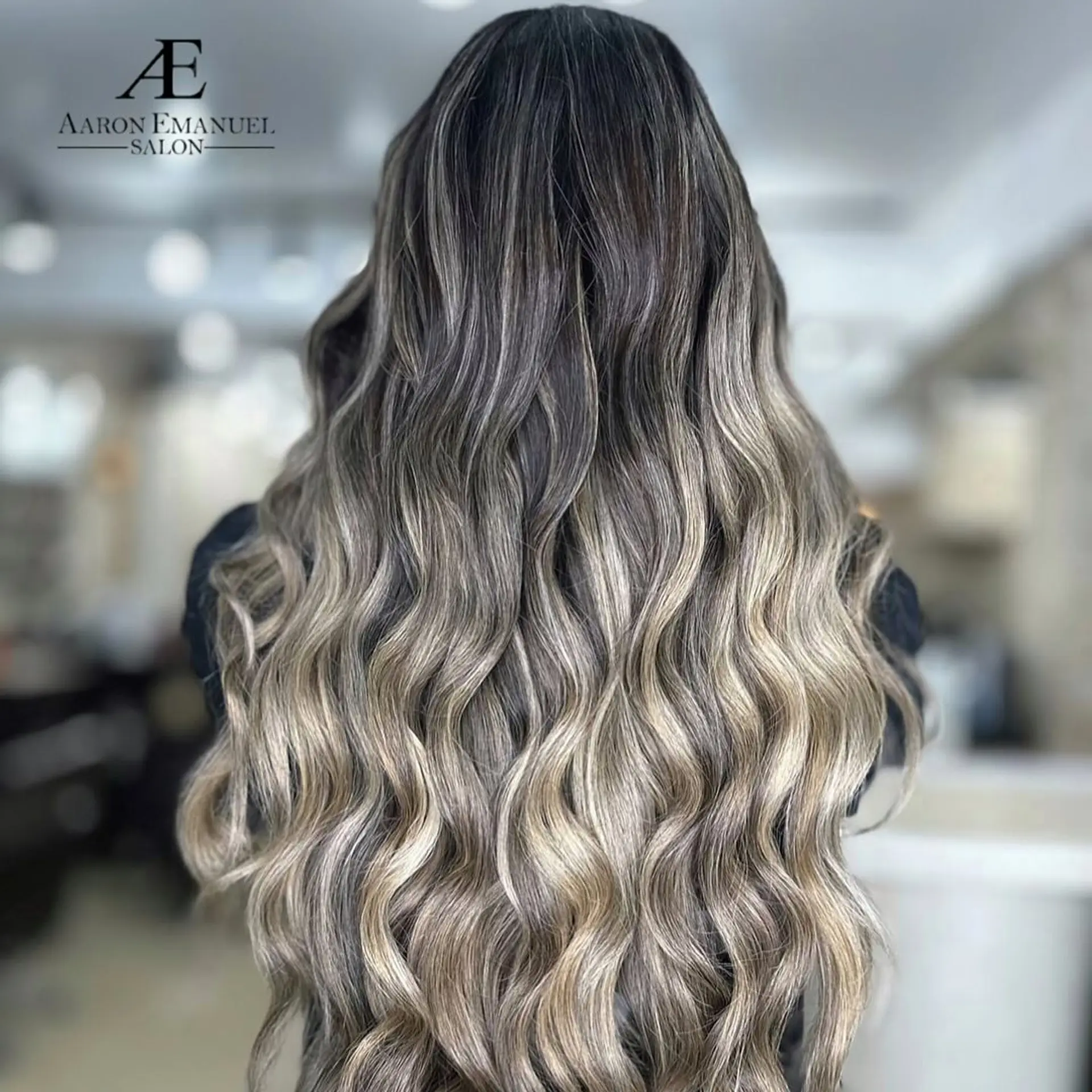 A very long wavy hairstyle with a dark root that melts into the blonde tips. 1