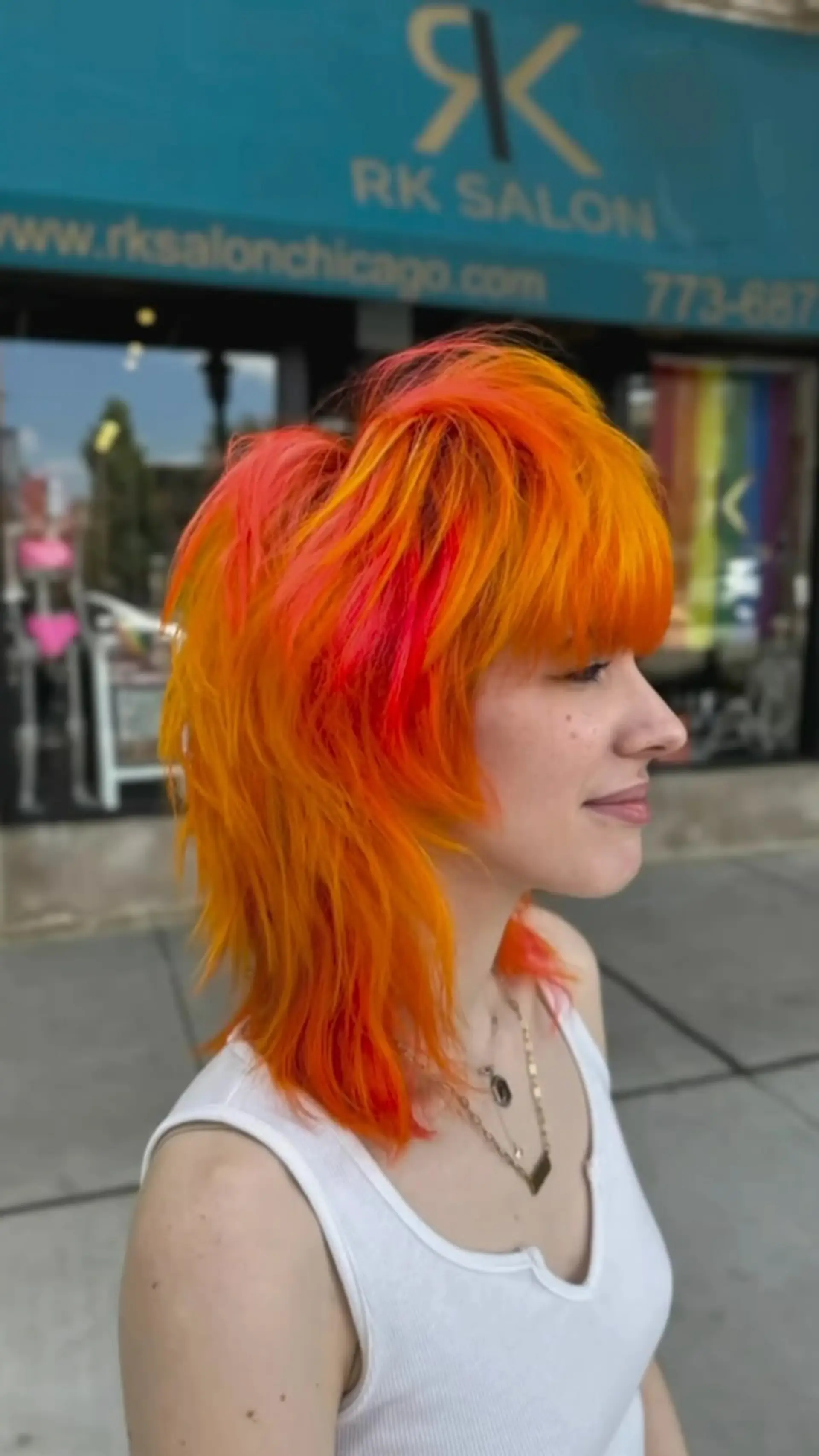 A vibrant sunset-toned shag mullet featuring vivid orange, neon pink, and yellow hues with textured layers and full bangs. 1