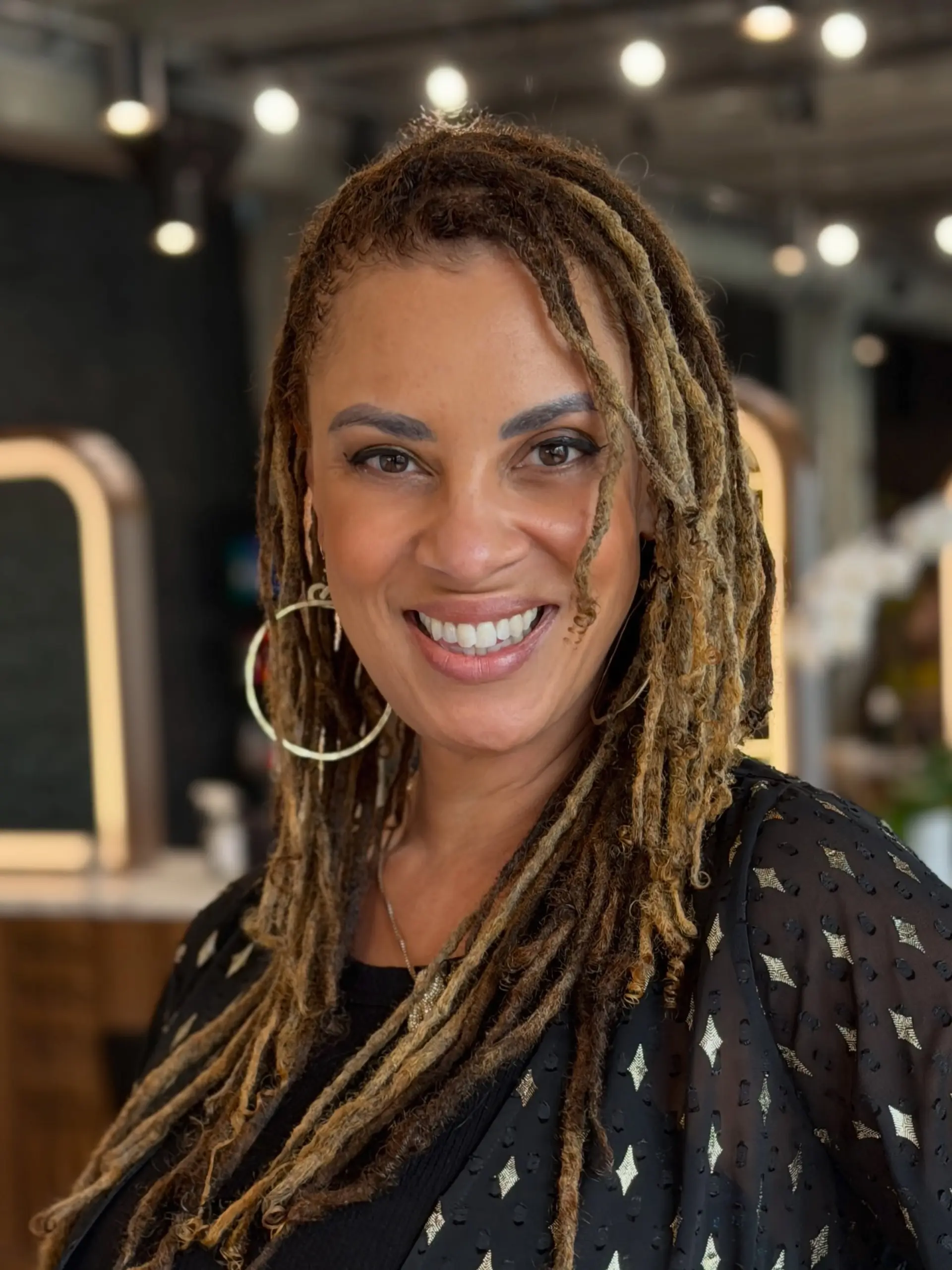 Long locs featuring a dimensional mix of warm honey and caramel blonde tones with refreshed roots. 1