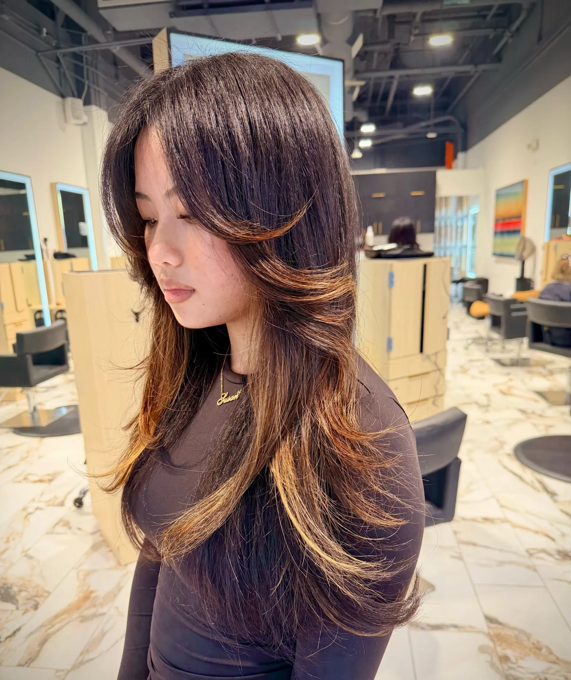Long dark brown hair featuring sweeping face-framing layers styled into a bouncy, voluminous blowout. 1