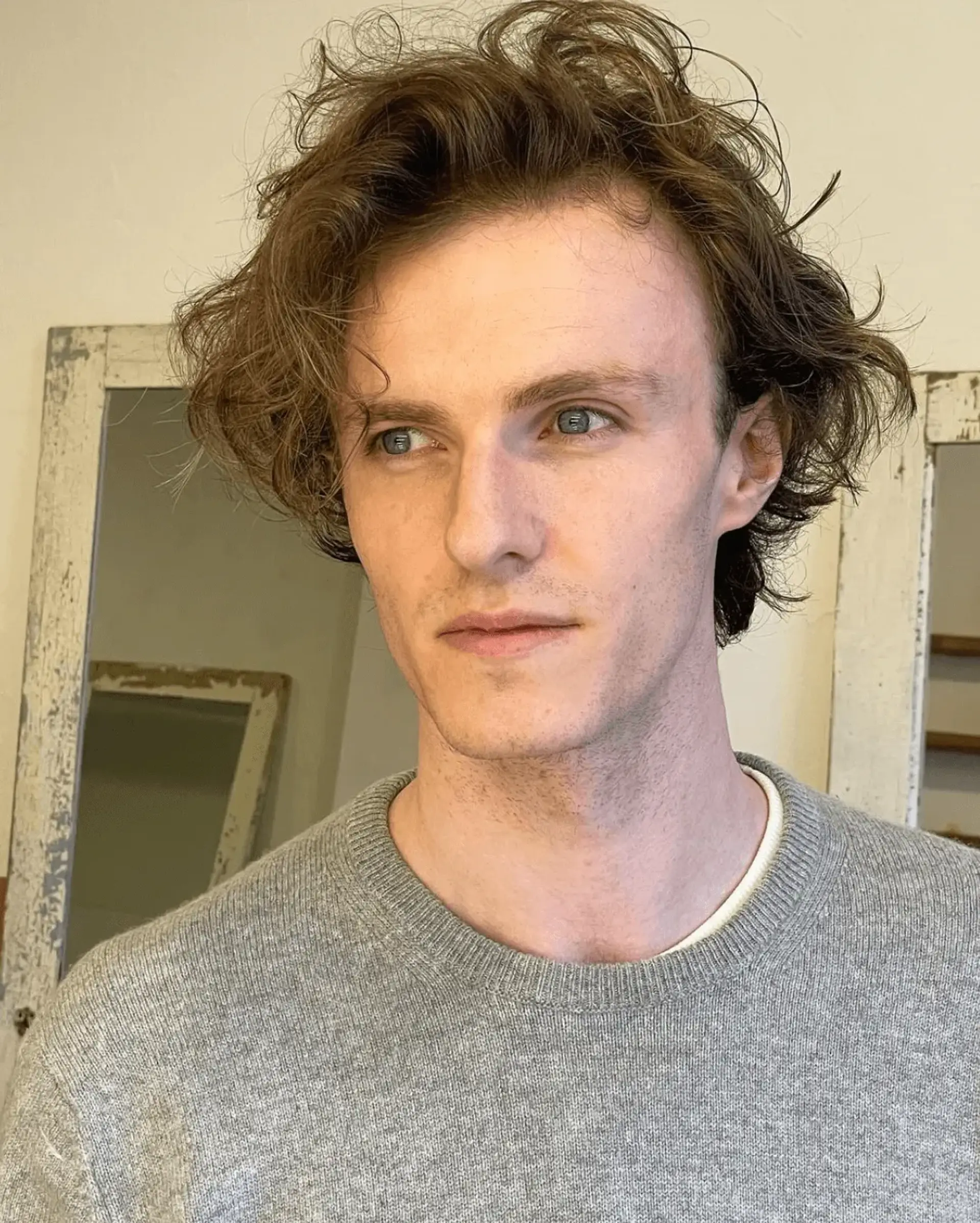 Medium length light brown wavy hair styled in a tousled, casual, and natural manner with a textured finish. 1