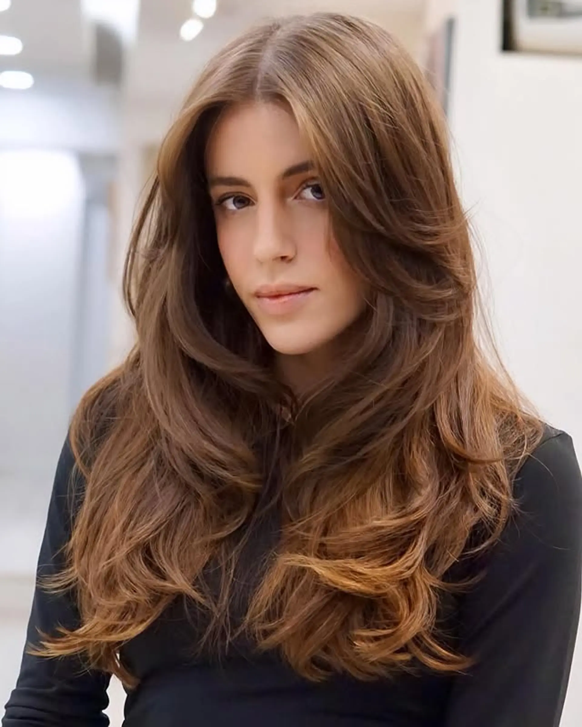 A long, wavy brunette hairstyle with layered and face-framing layers. 1