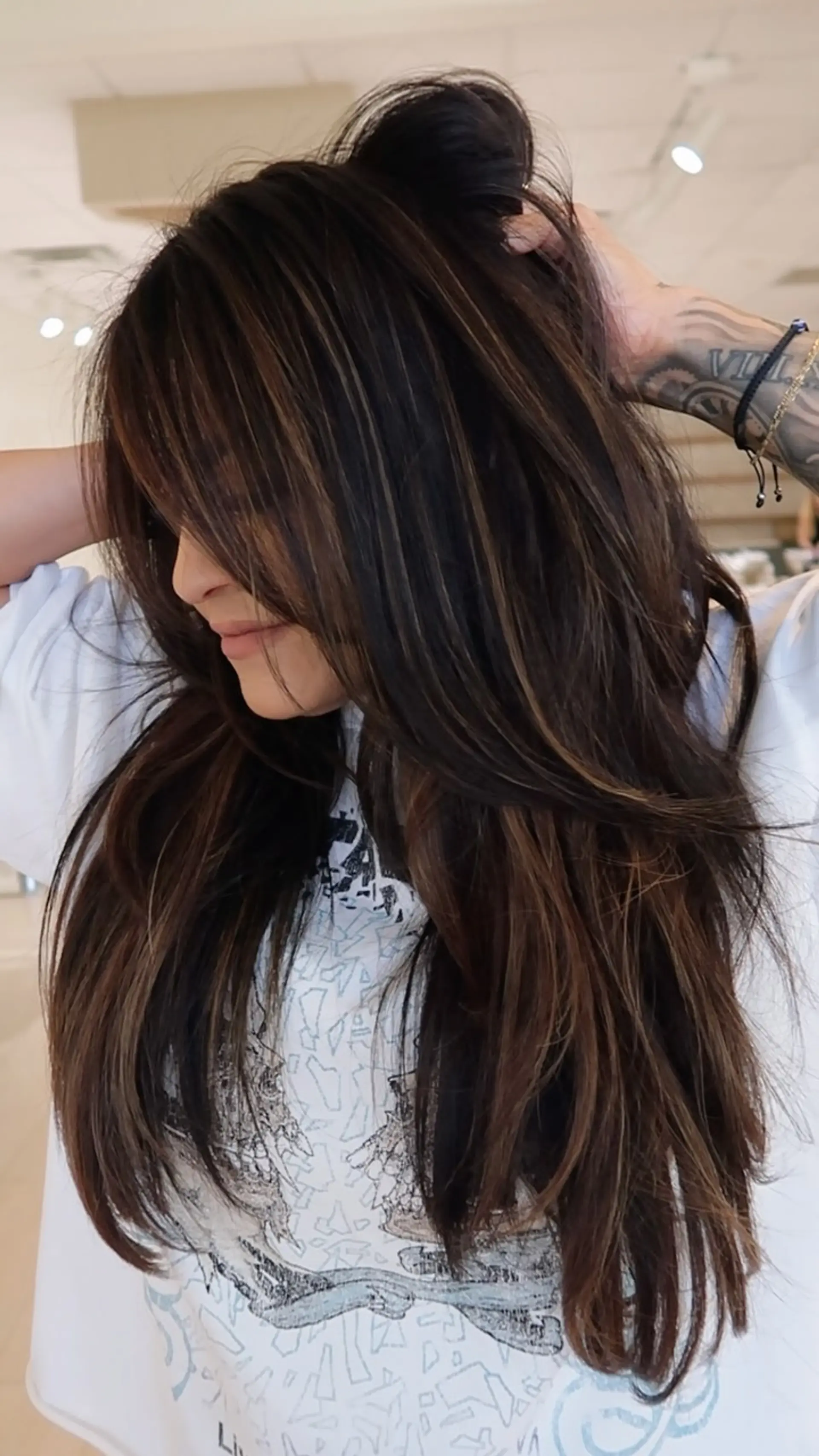 Long, voluminous brunette hair featuring soft dimensional highlights, face-framing fringe, and feathered layers. 1